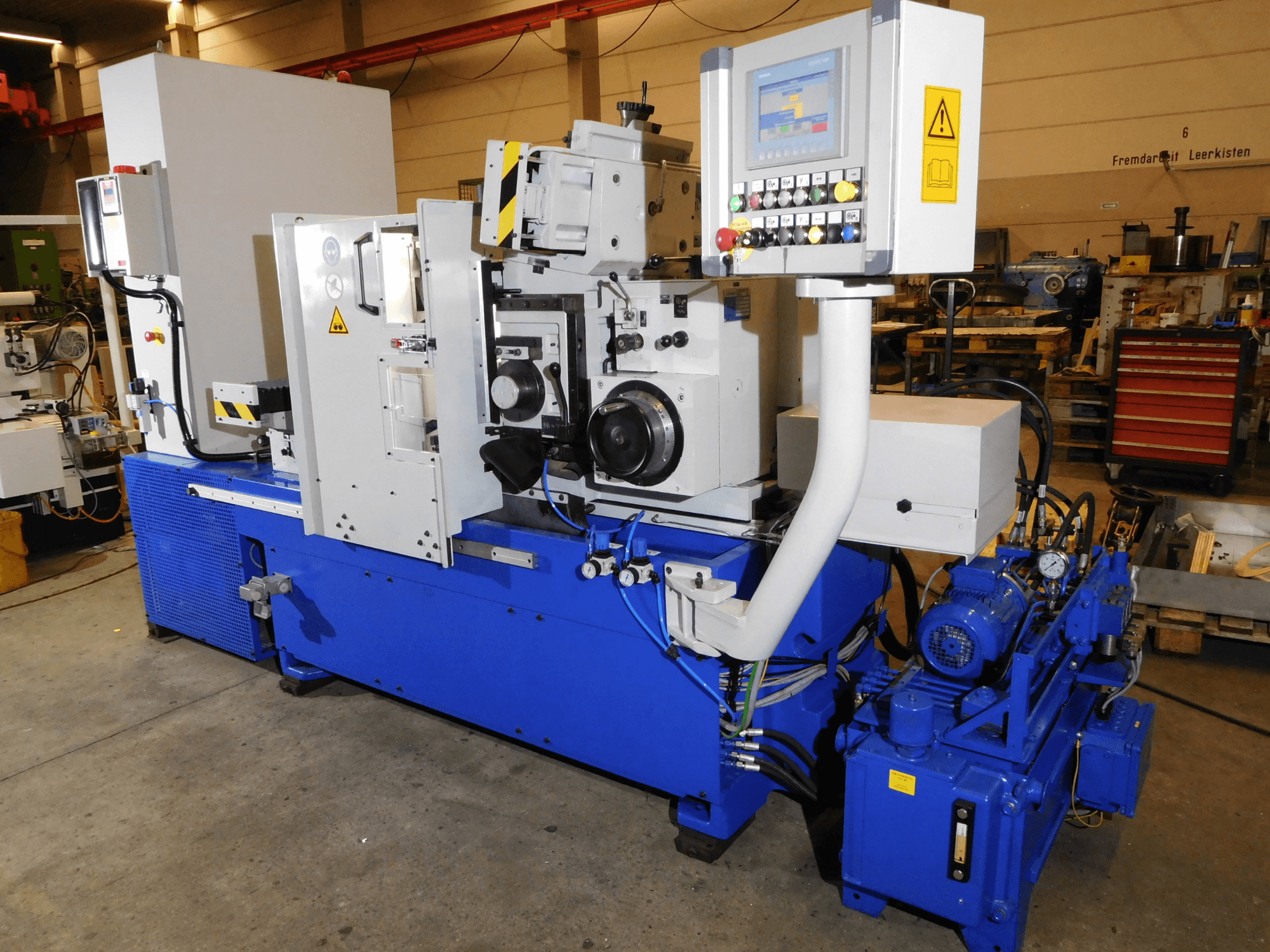Machine à meuler sans centre Schaudt Mikrosa SASL 125, vue de côté, comprenant les commandes et le corps bleu industriel avec les composants du moteur.