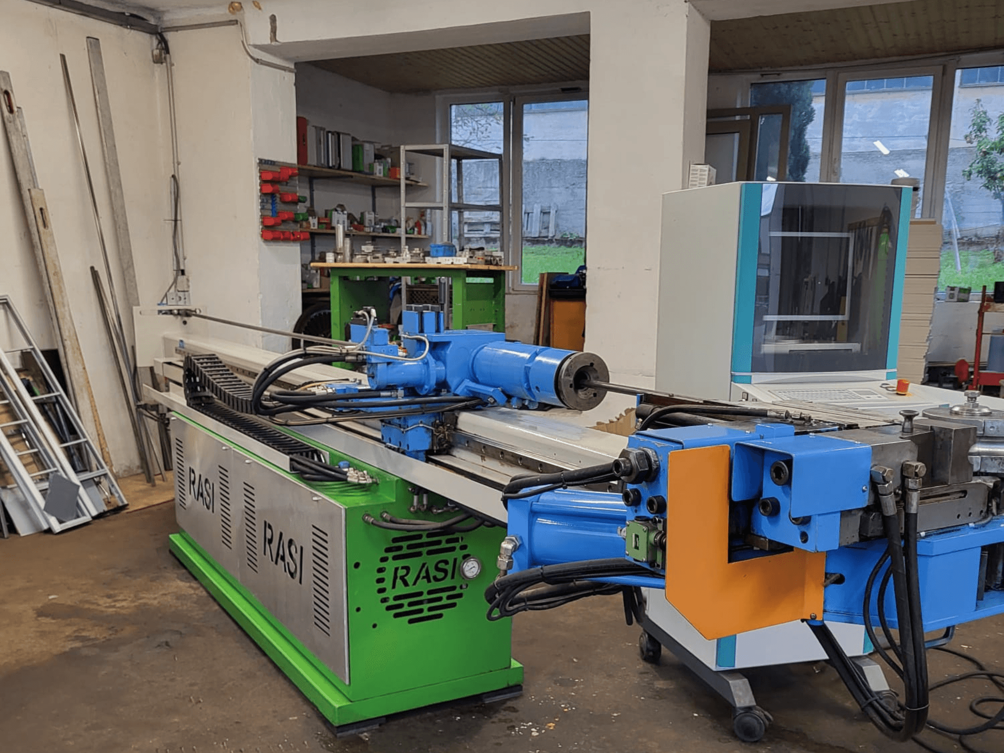 Machine-outil Rasi S 80.6 L G-V3C50 dans un atelier, vue latérale montrant les composants bleus et verts et le panneau de commande.