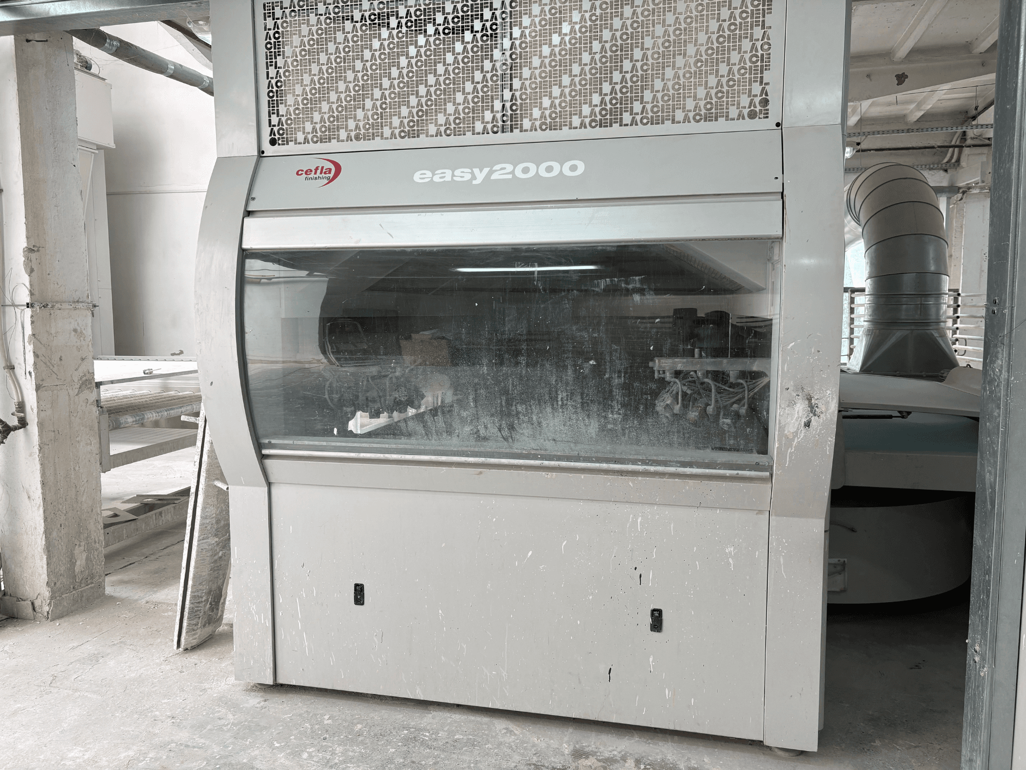 Vue de face de la machine Cefla EASY 2000 D, dotée d'un grand panneau transparent, d'une surface poussiéreuse et de composants internes visibles.