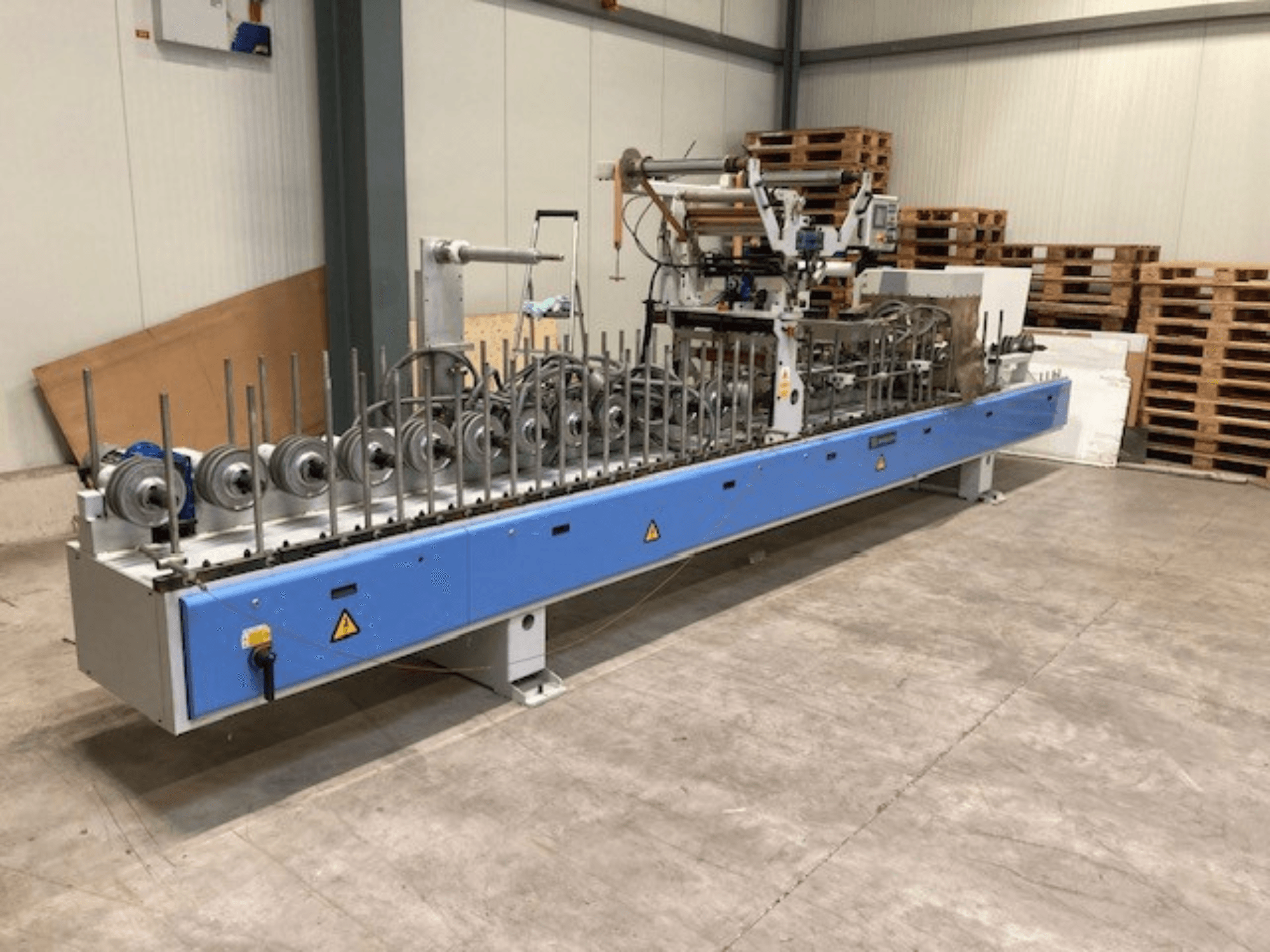 Presse à plastifier Barberan PUR 46 L, vue de face, avec plusieurs rouleaux et une base bleue dans un entrepôt.