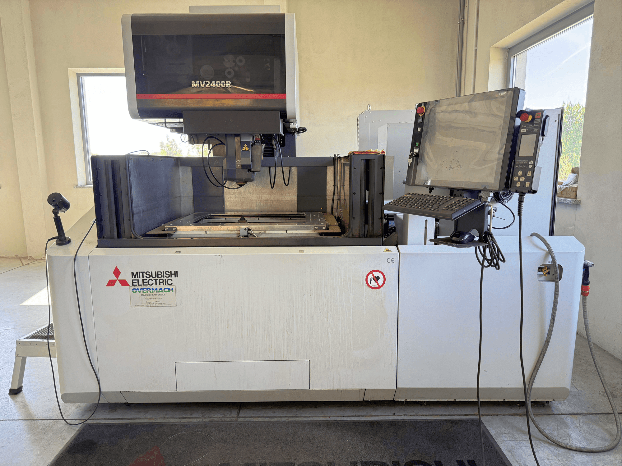 Vue de face d'une machine d'électroérosion à fil Mitsubishi MV2400R, avec son panneau de commande, son espace de travail et ses panneaux de sécurité.