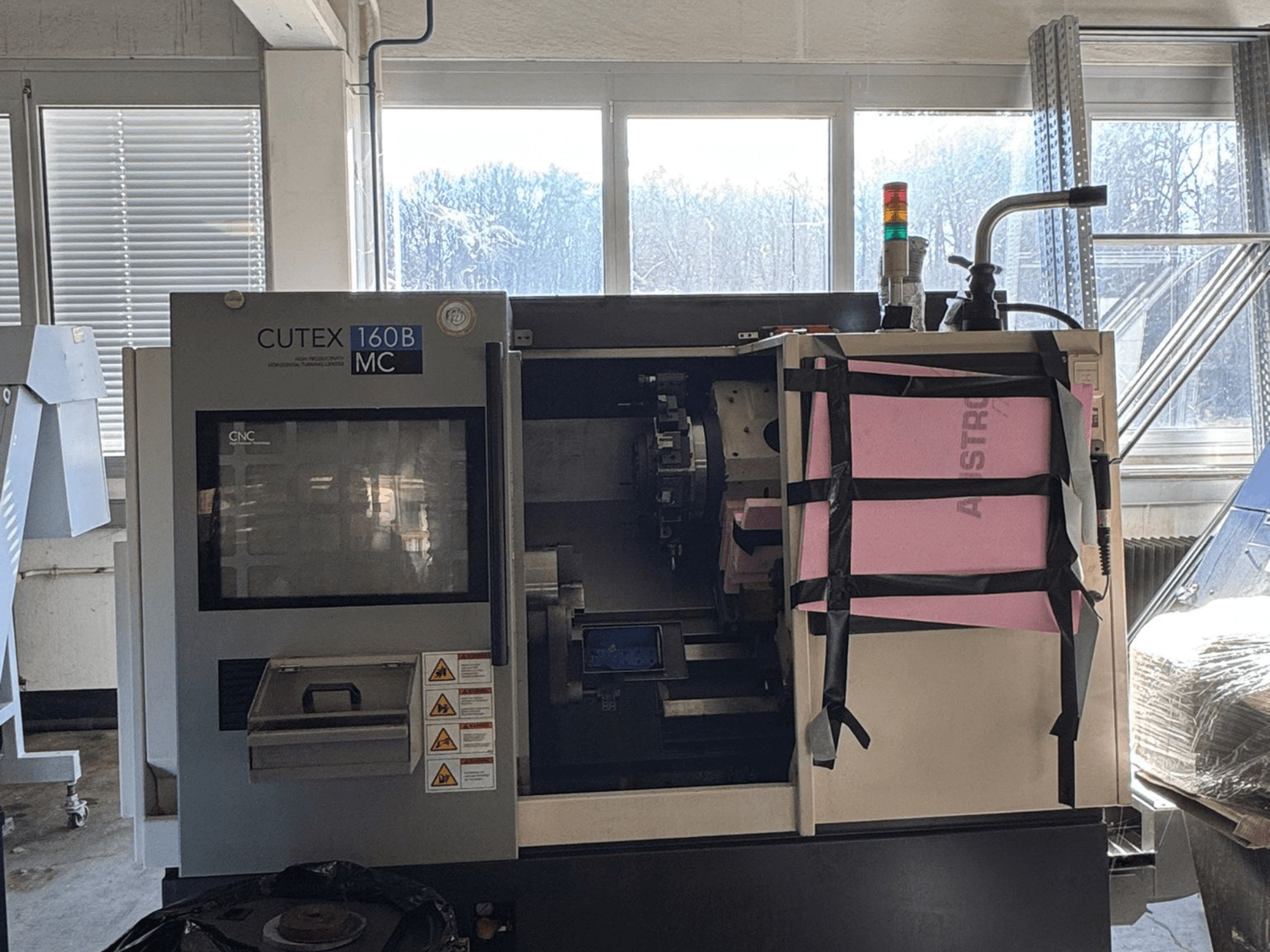 Vue de face du tour horizontal HWACHEON CUTEX 160 B VDI, avec son panneau de commande et son réservoir de liquide de refroidissement, équipé d'un voyant de sécurité.