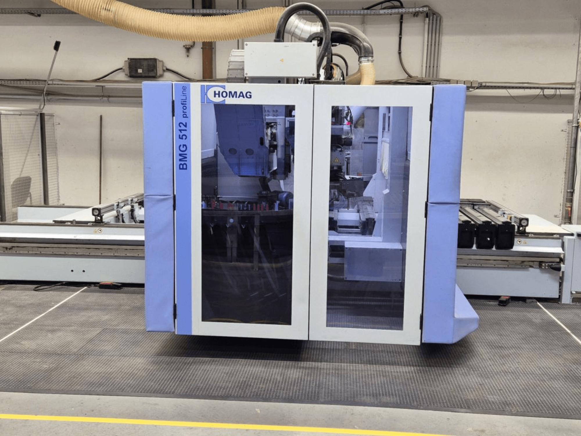 Machine CNC HOMAG BMG 512 ProfiLine, vue de face, avec panneau en verre, outils de précision visibles et environnement industriel.