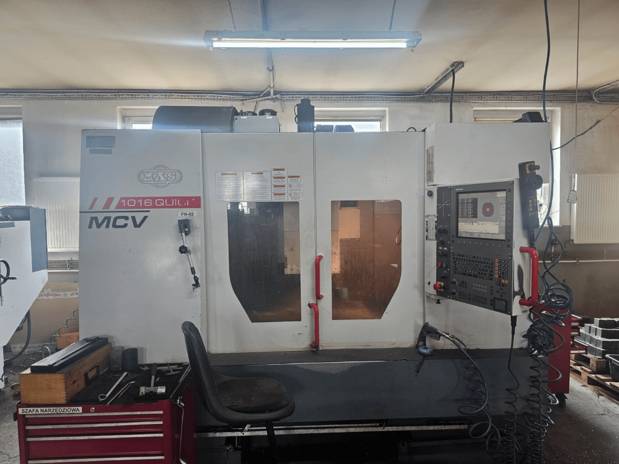Machine CNC MVS MCV 1016 QUILL, vue de face, comprenant le panneau de commande, le tiroir à outils et l'espace de travail avec les outils.