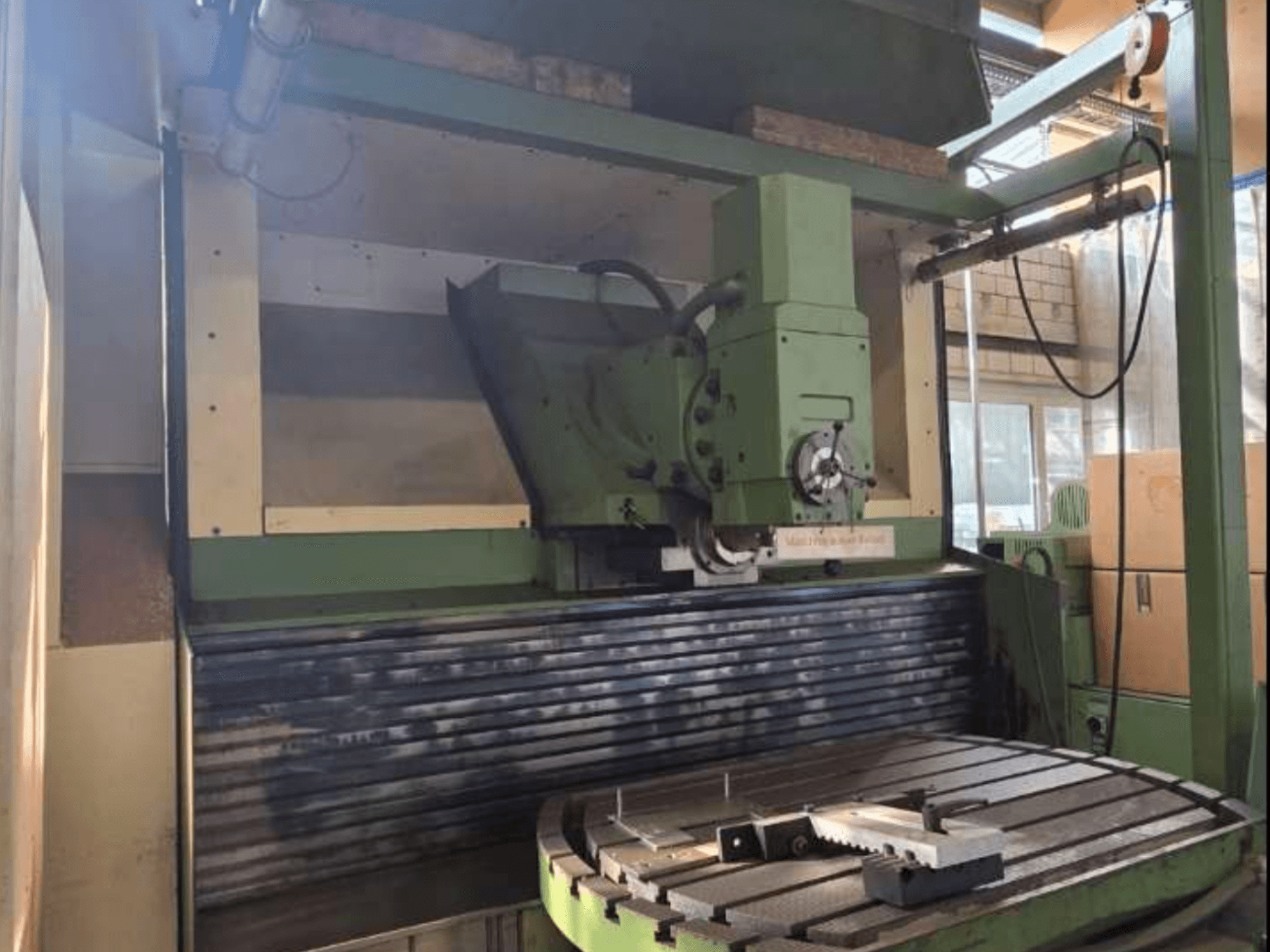 Centre d'usinage universel MAHO MH1000 C en vue de face, montrant la structure verte, la broche et la table rotative avec une pièce à usiner.