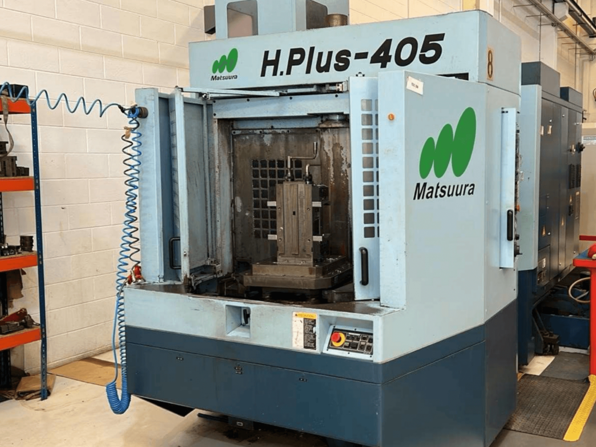 Vue de face d'un centre d'usinage horizontal Matsuura H.Plus 405, porte ouverte, montrant l'espace de travail et le panneau de commande.