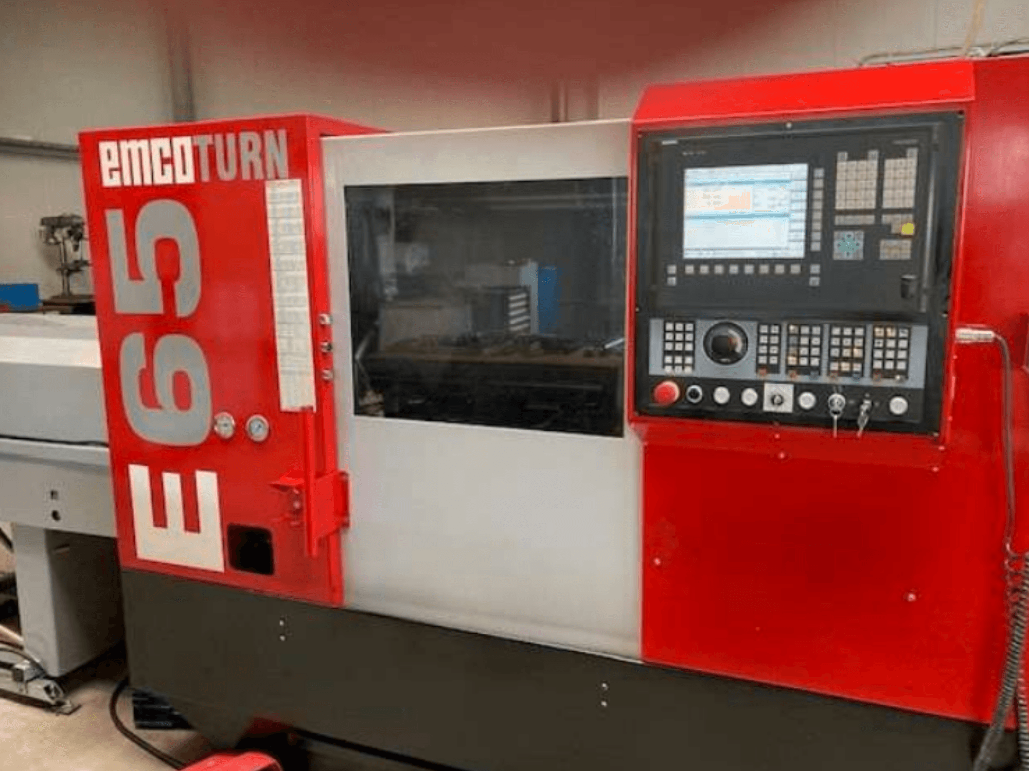 Tour CNC EMCO Turn E65, vue de face montrant le panneau de commande, le grand écran et la zone de travail derrière la vitre.