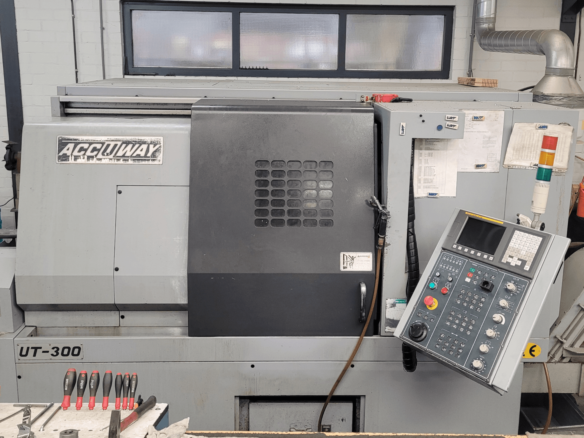 Machine CNC Accuway UT-300 vue de face, comportant un panneau de commande et divers boutons opérationnels, dans un atelier.