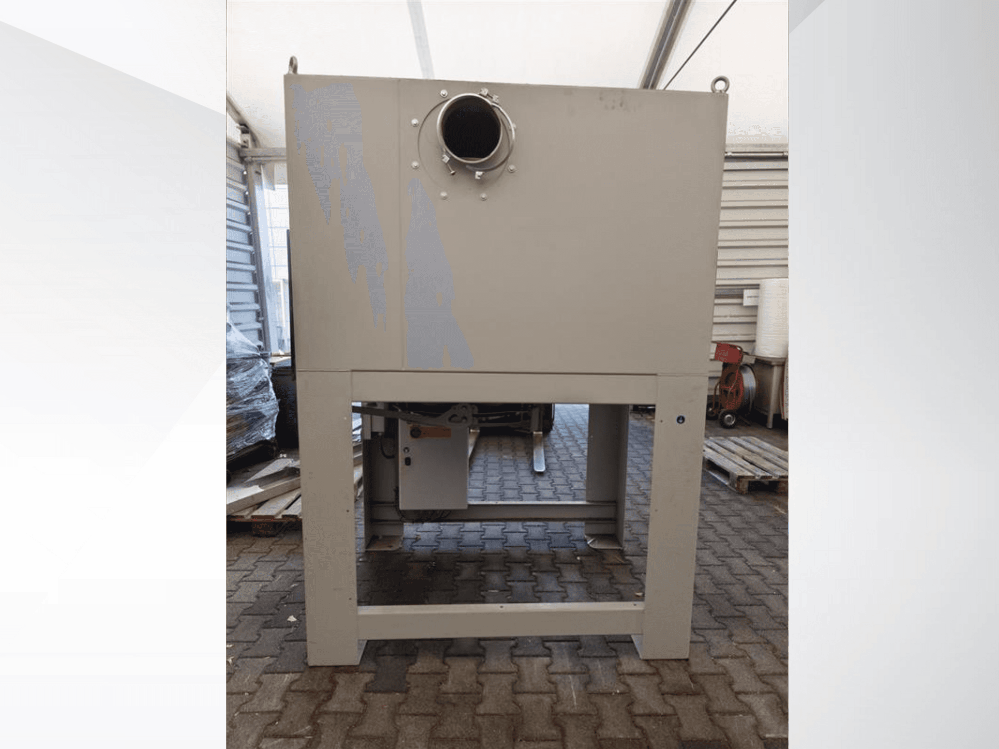 Dépoussiéreur industriel gris vu de face, doté d'une grande ouverture ronde et monté sur une base solide.