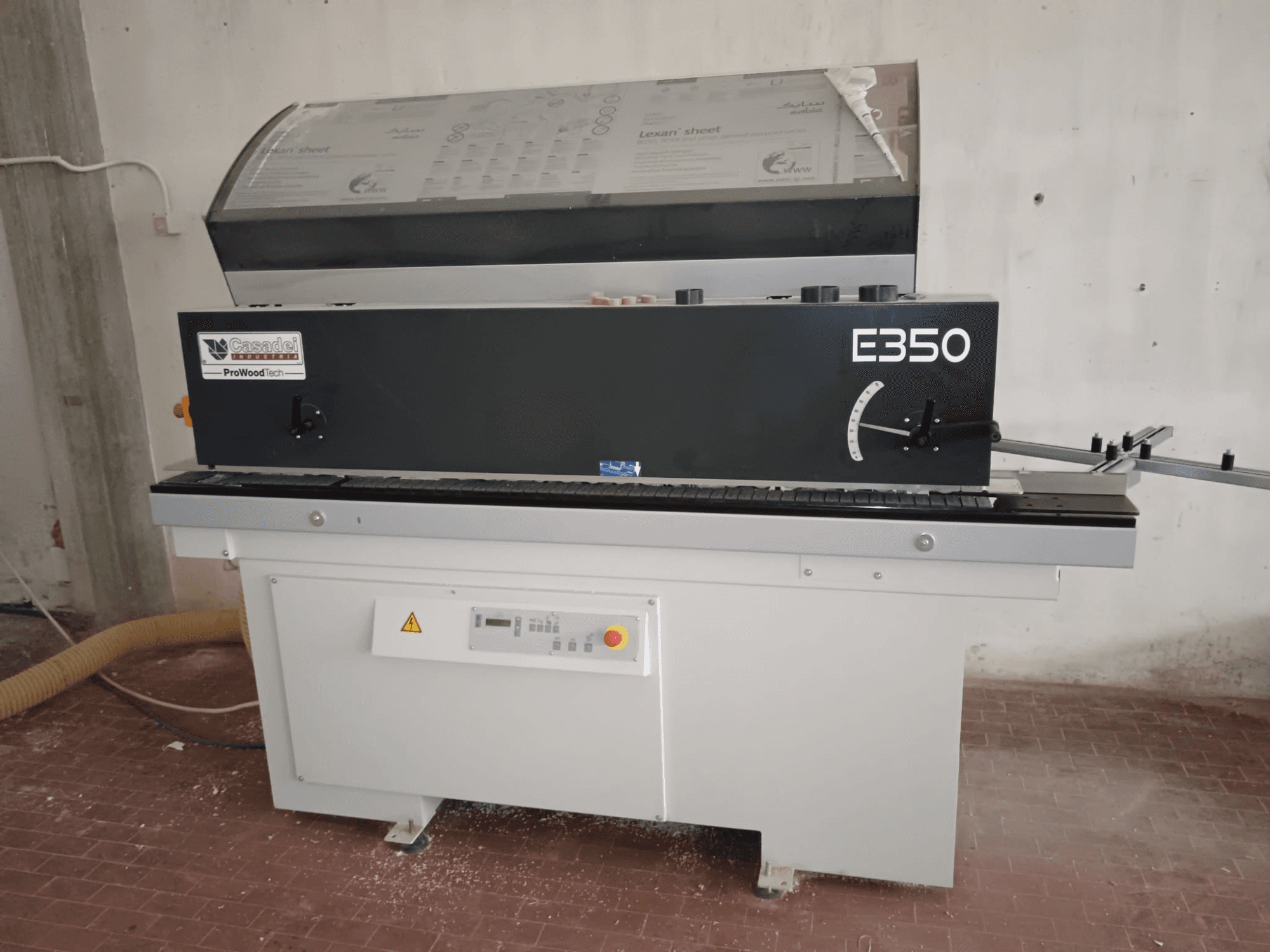 Cesaroli ProWoodtech E350, vue latérale d'une machine à travailler le bois avec panneau de commande et accumulation de poussière, montée sur une base blanche.