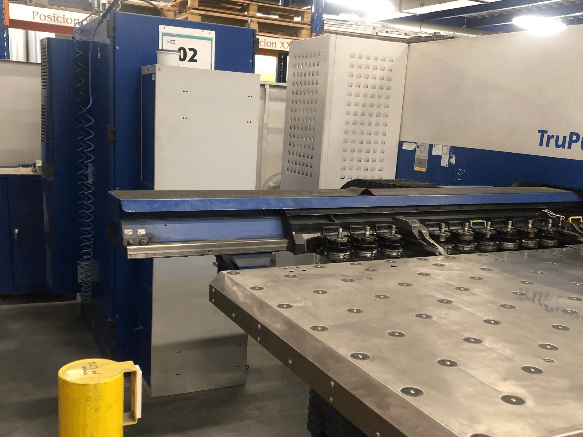 Poinçonneuse CNC TRUMPF TruPunch 5000, vue de face montrant la tourelle d'outils et le panneau de commande, avec une table de travail métallique à proximité.