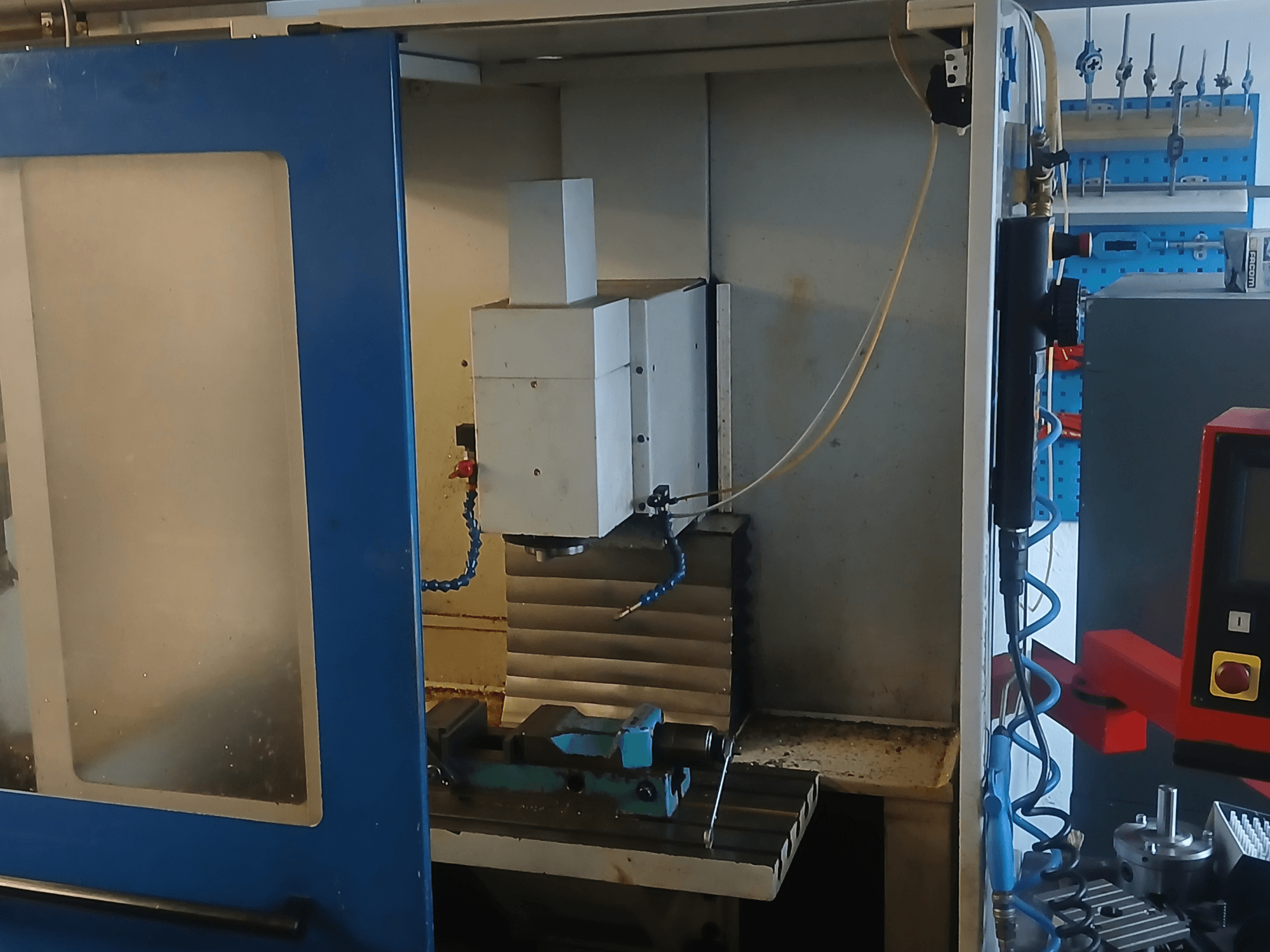 Centre d'usinage vertical MACMON M 454 V vu de face, mettant en évidence la broche et la zone d'usinage, avec les outils à proximité.