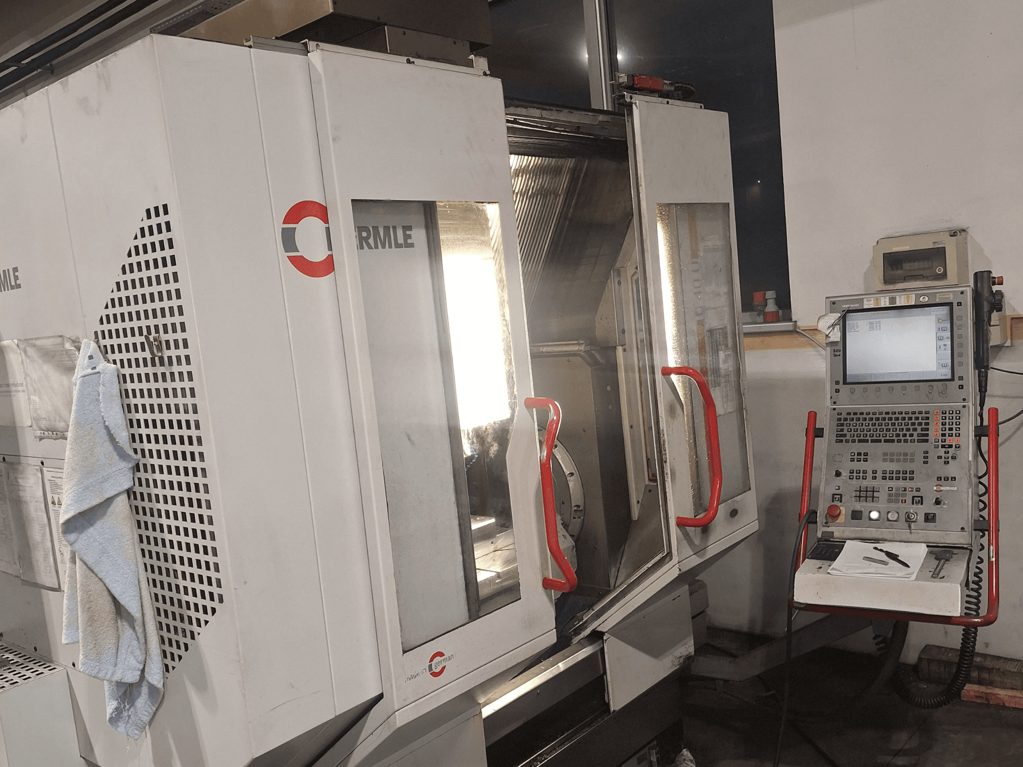 Machine CNC de la marque Cormile, vue de face montrant les portes partiellement ouvertes et le panneau de commande avec écran et boutons.