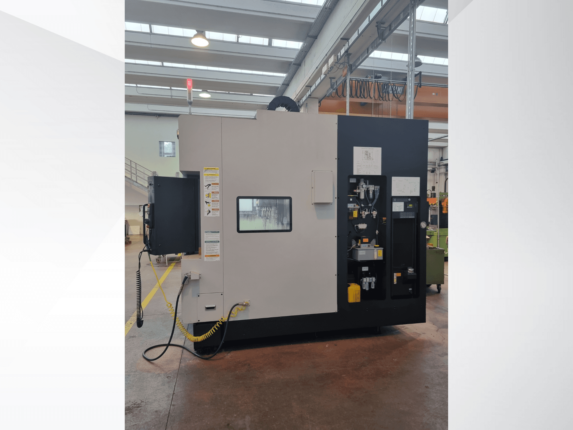 Machine industrielle vue de côté, comportant un panneau de commande avec des boutons, des indicateurs et une étiquette d'avertissement de sécurité.