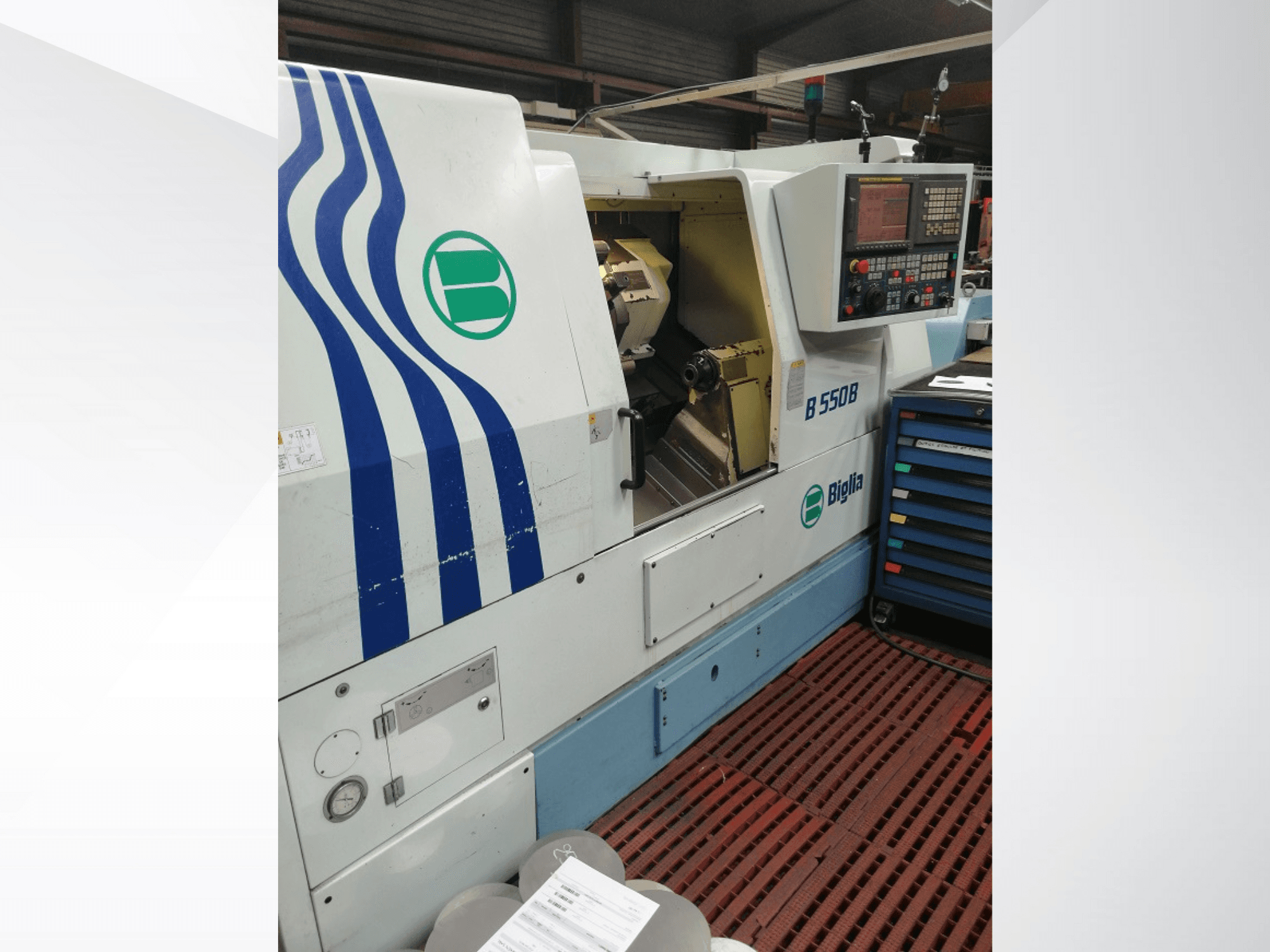 Tour CNC Biglia B 550 B présenté de face, avec le panneau de commande, la zone de travail du métal et le stockage d'outils colorés.