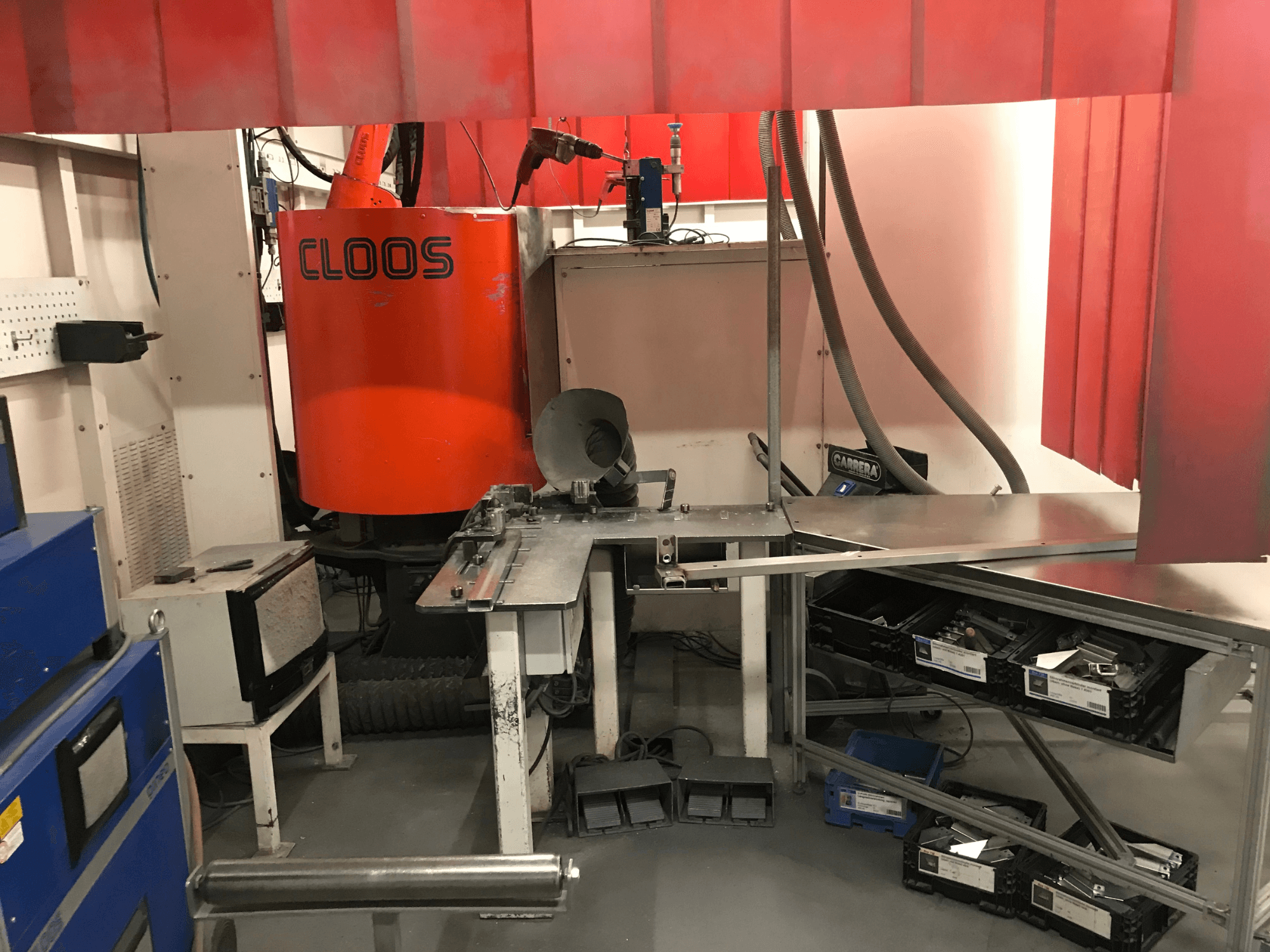 Système d'atelier de soudage de DESSAUER : vue de face montrant le bras robotisé, la surface de travail métallique et les zones de stockage dans un environnement d'atelier.