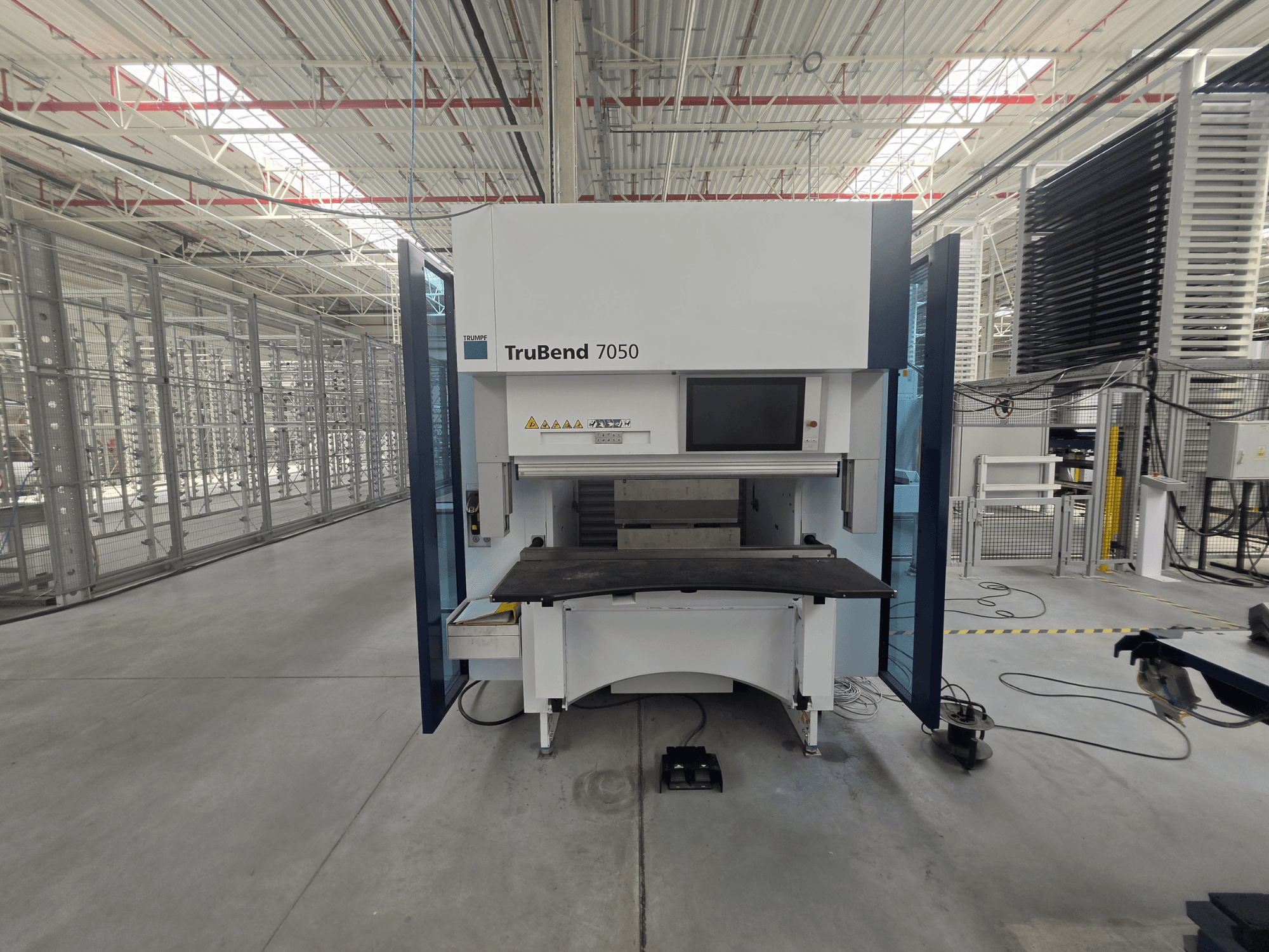 Vue de face de la presse plieuse TRUMPF TruBend 7050, mettant en avant le panneau de commande et la table de travail dans un environnement industriel bien éclairé.