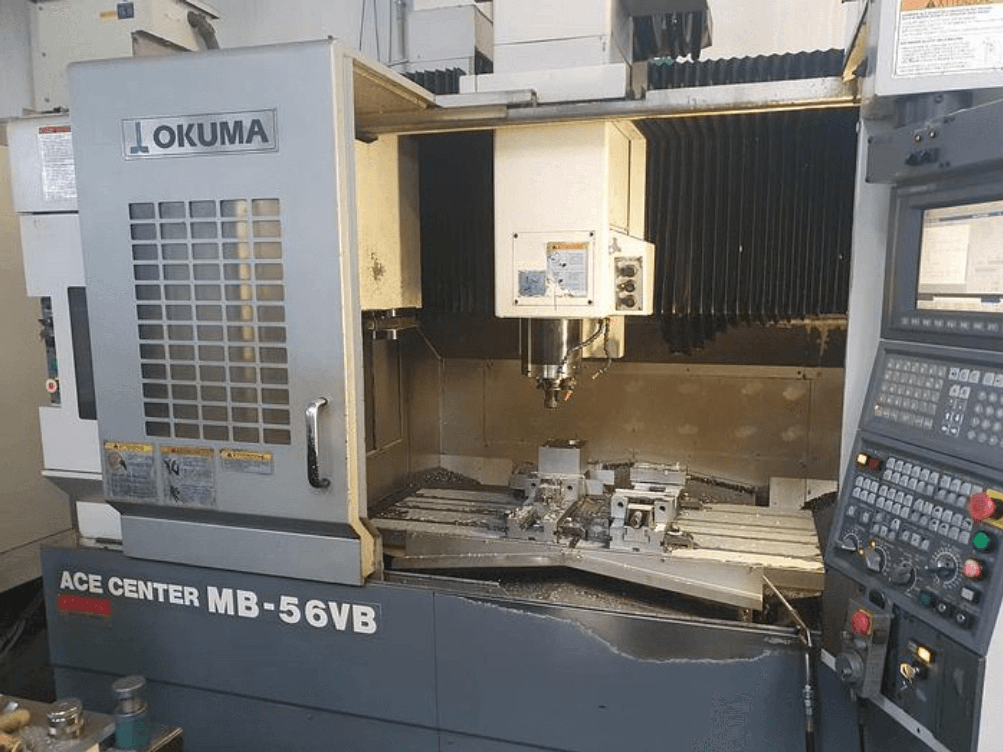 Fraiseuse CNC Okuma ACE CENTER MB-56VB vue de face, montrant le panneau de commande et la zone d'usinage.