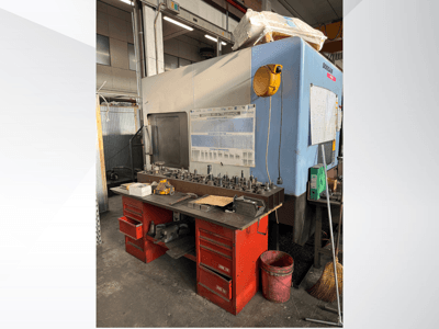 Centre d'usinage Doosan avec un établi rouge et un espace de rangement, présentant les outils et l'équipement, vu de face.