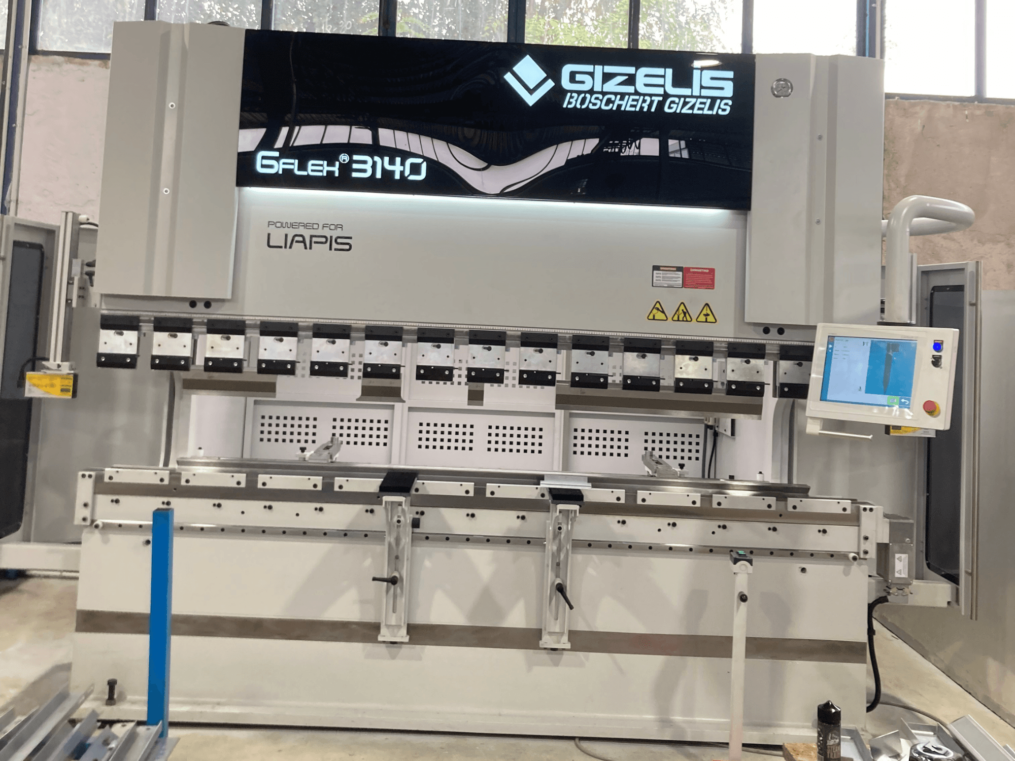 Presse hydraulique GIZELIS G-FLEX 3140 vue de face avec écran de contrôle, comportant plusieurs outils de pliage et des étiquettes de sécurité.