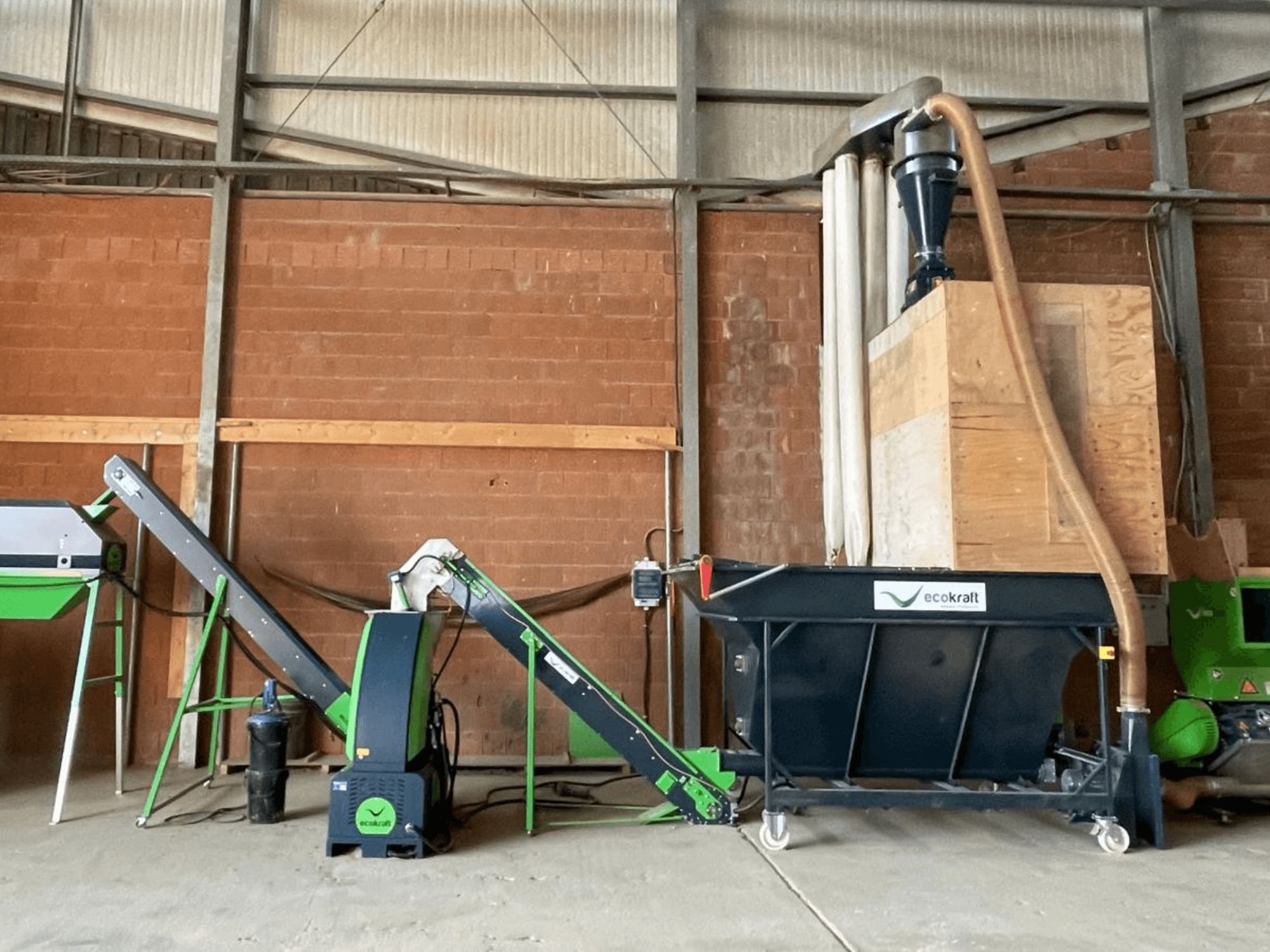 Machine-outil ECOKRAFT LP 22 dans un entrepôt, équipée d'un convoyeur et d'un système de dépoussiérage. Vue de profil mettant en évidence les composants fonctionnels.