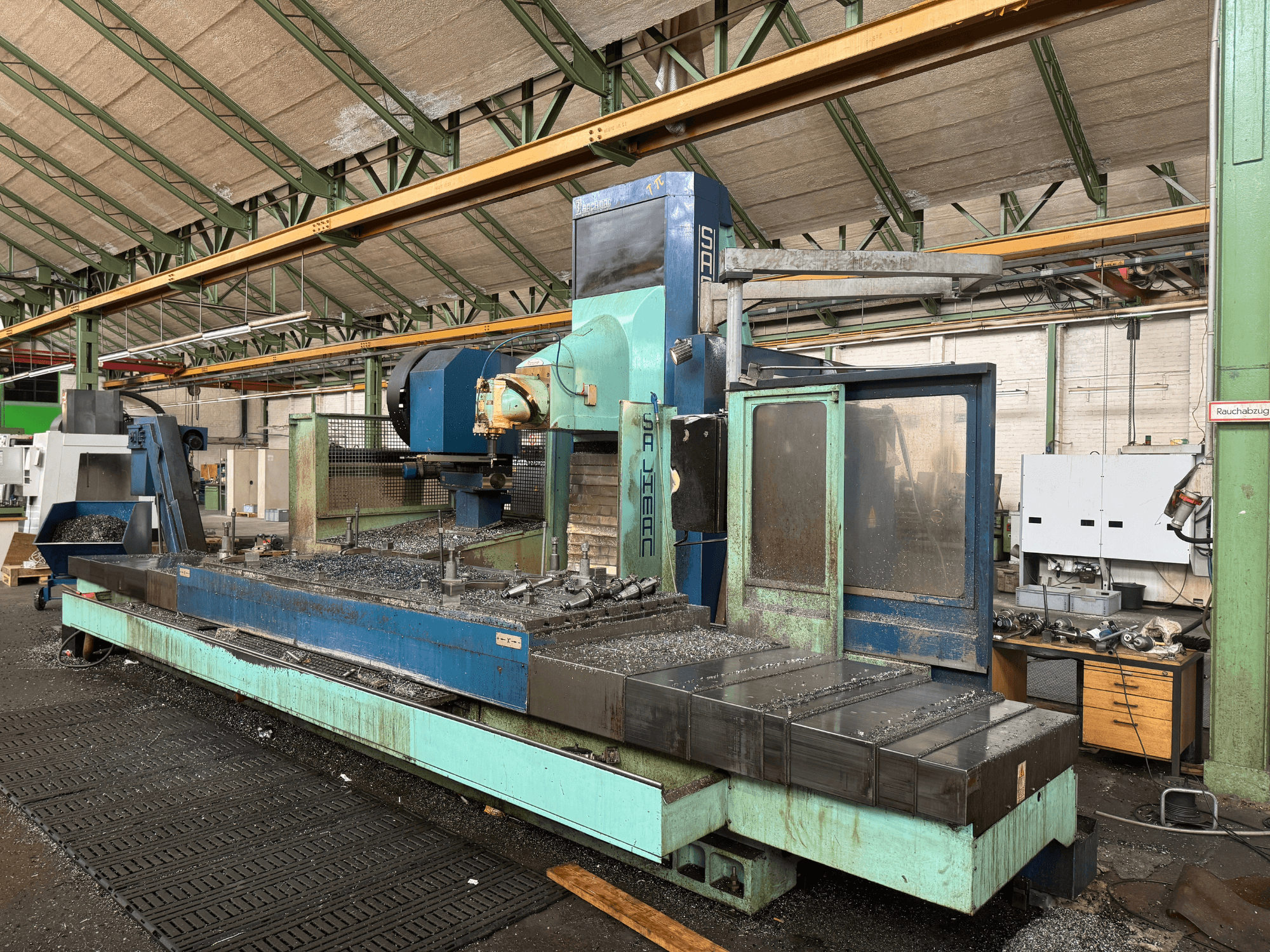 Fraiseuse Salvador en usine, vue de face, avec un schéma de couleurs bleu et vert, montrant des copeaux de métal sur le banc.