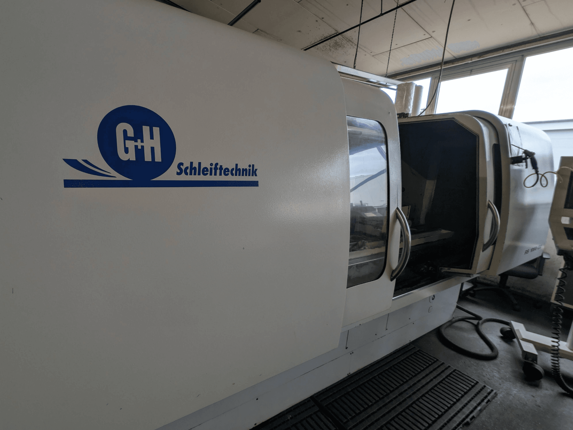 Rectifieuse cylindrique GEIBEL & HOTZ RS 1000 CU, vue latérale montrant le panneau de commande et la porte d'accès ouverte.