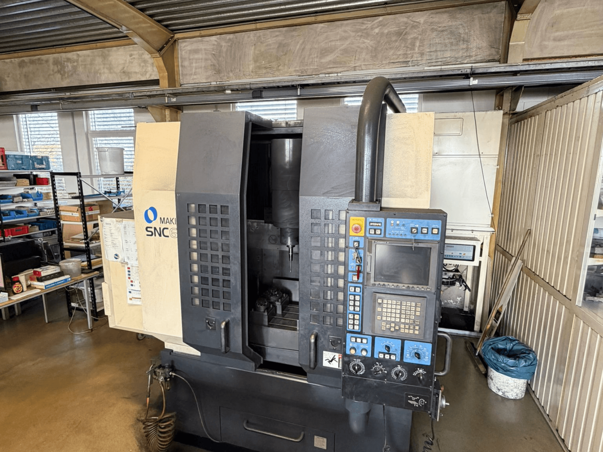 Centre d'usinage vertical Makino SNC 64-A15 en vue frontale, présentant le panneau de commande, la zone d'usinage et l'espace de travail industriel.