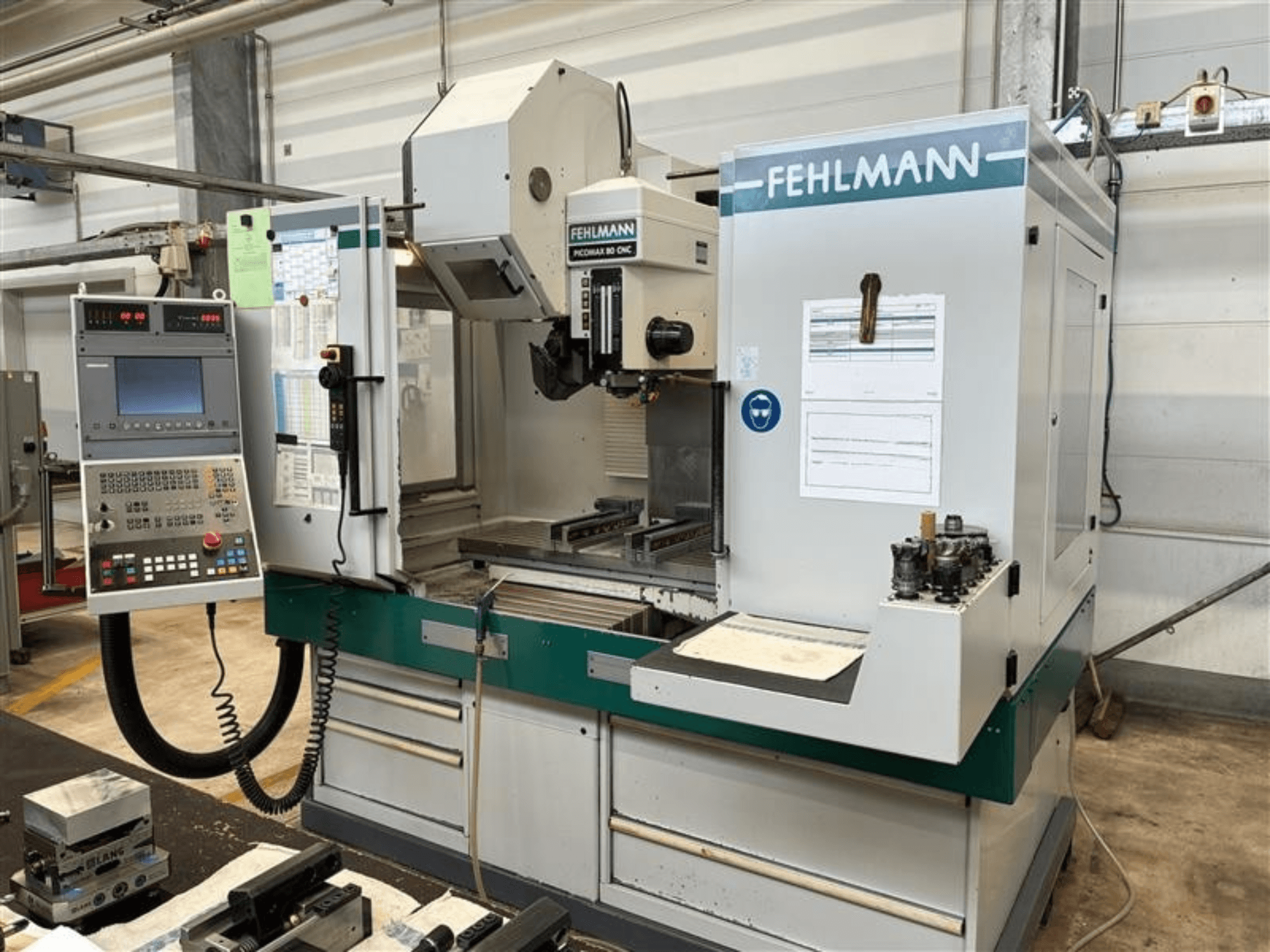 Centre d'usinage vertical FEHLMANN PICOMAX 80 CNC-W 2/3 vu de face, avec son panneau de commande et son espace d'usinage.