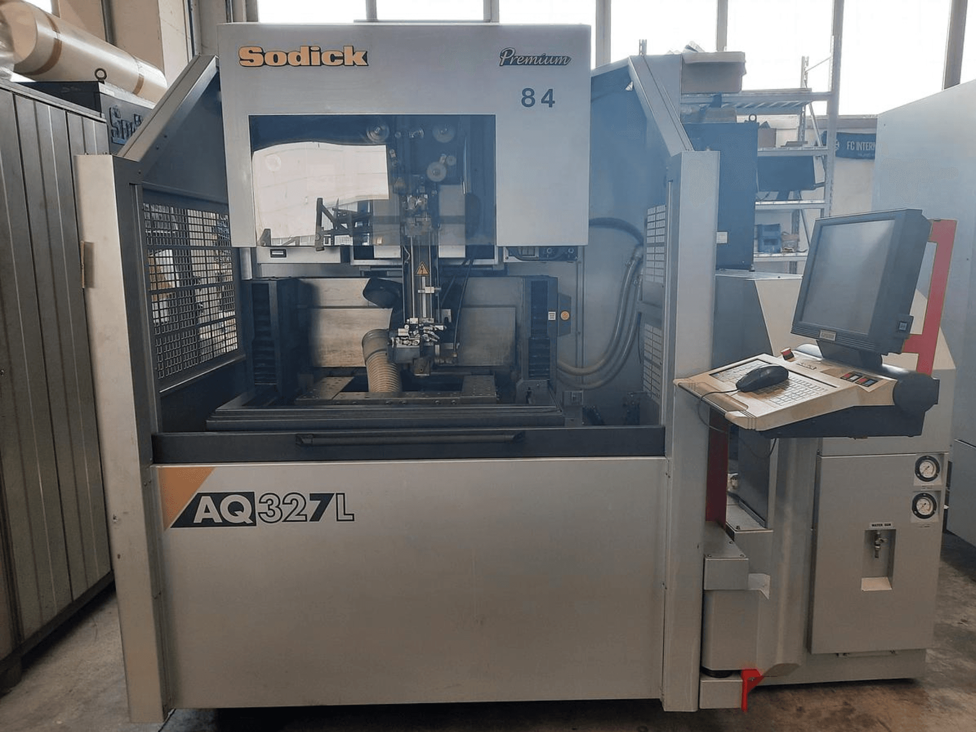Machine Sodick AQ327L vue de face, avec panneau de commande, interface utilisateur et zone de coupe visible à l'intérieur.