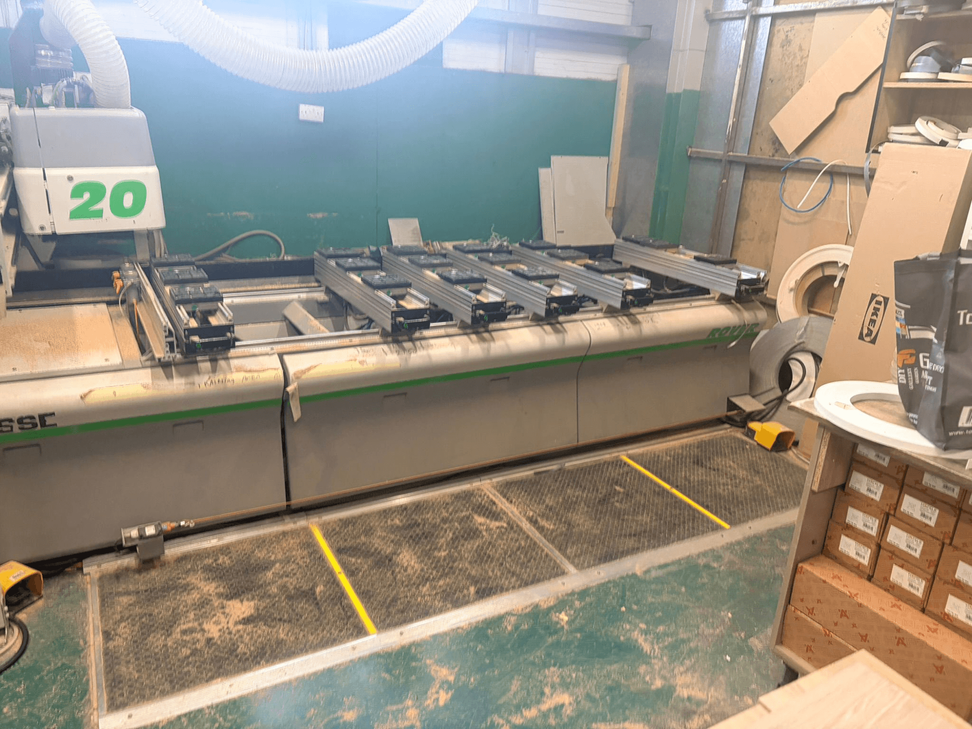 Centre d'usinage du bois CNC BIESSE ROVER 20, vue de face, avec le système de rails, les commandes et la sciure de bois visible sur la surface.