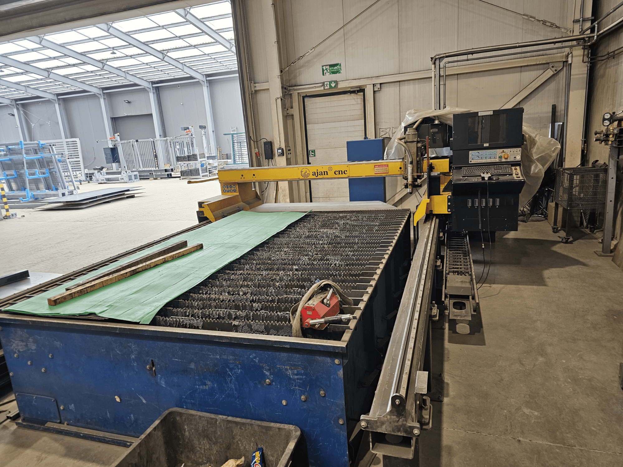 AJAN PP16011 Machine de découpe plasma automatique en vue latérale, comprenant une table de découpe et un panneau de commande, dans un environnement d'atelier.