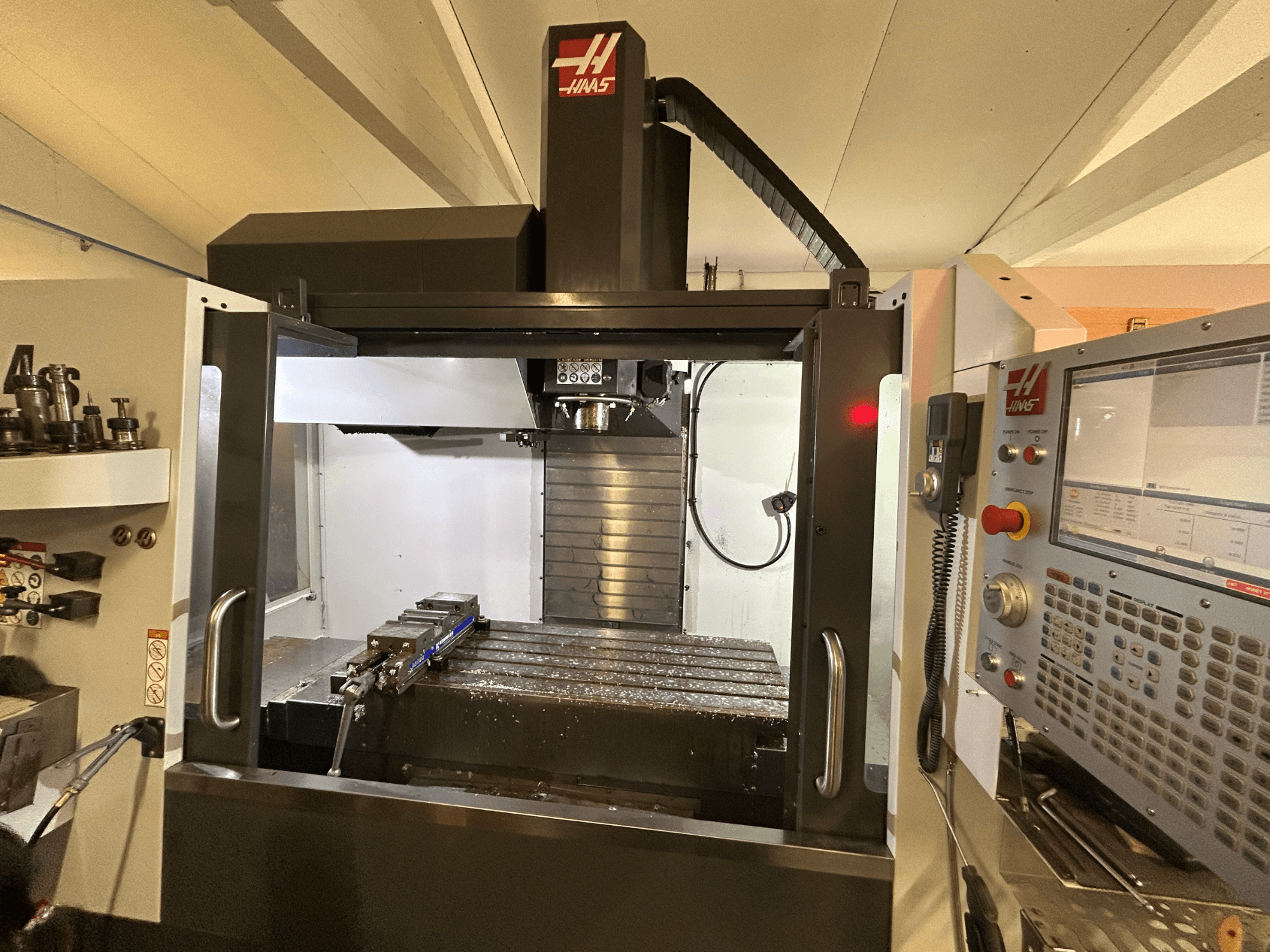 Centre d'usinage vertical HAAS VF-4SS, vue de face, montrant le panneau de commande, le porte-outil et la zone de travail avec des copeaux de métal.