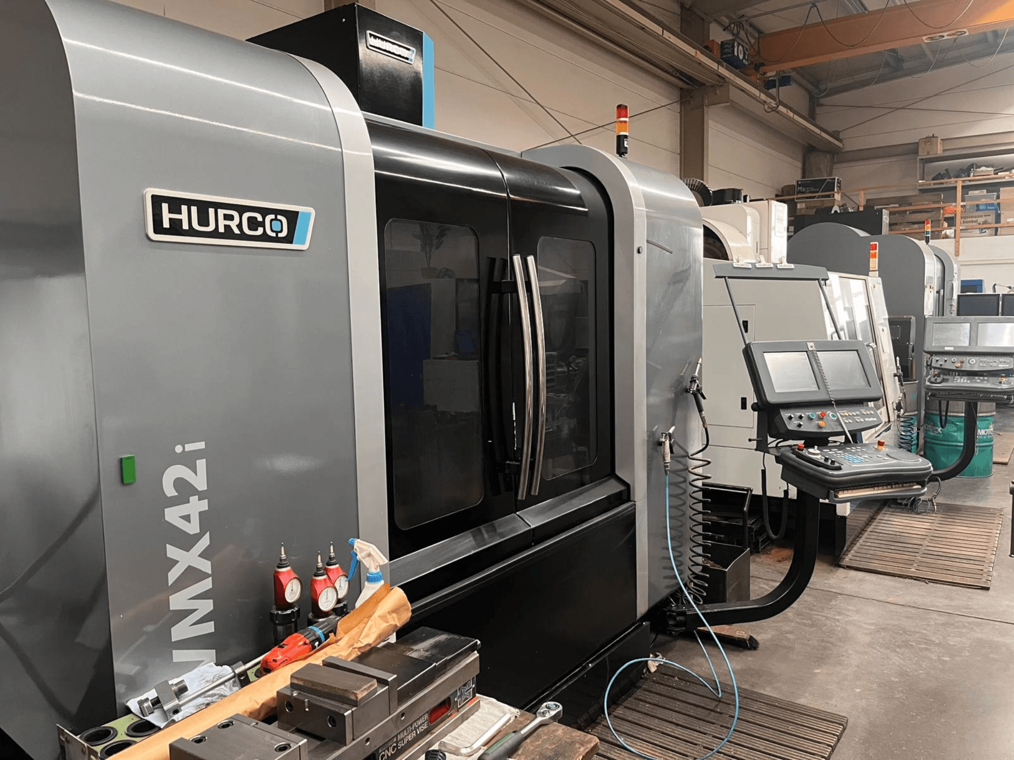 Machine CNC Hurco VMX42i dans un atelier, vue de face, avec panneau de commande et divers outils sur l'établi.