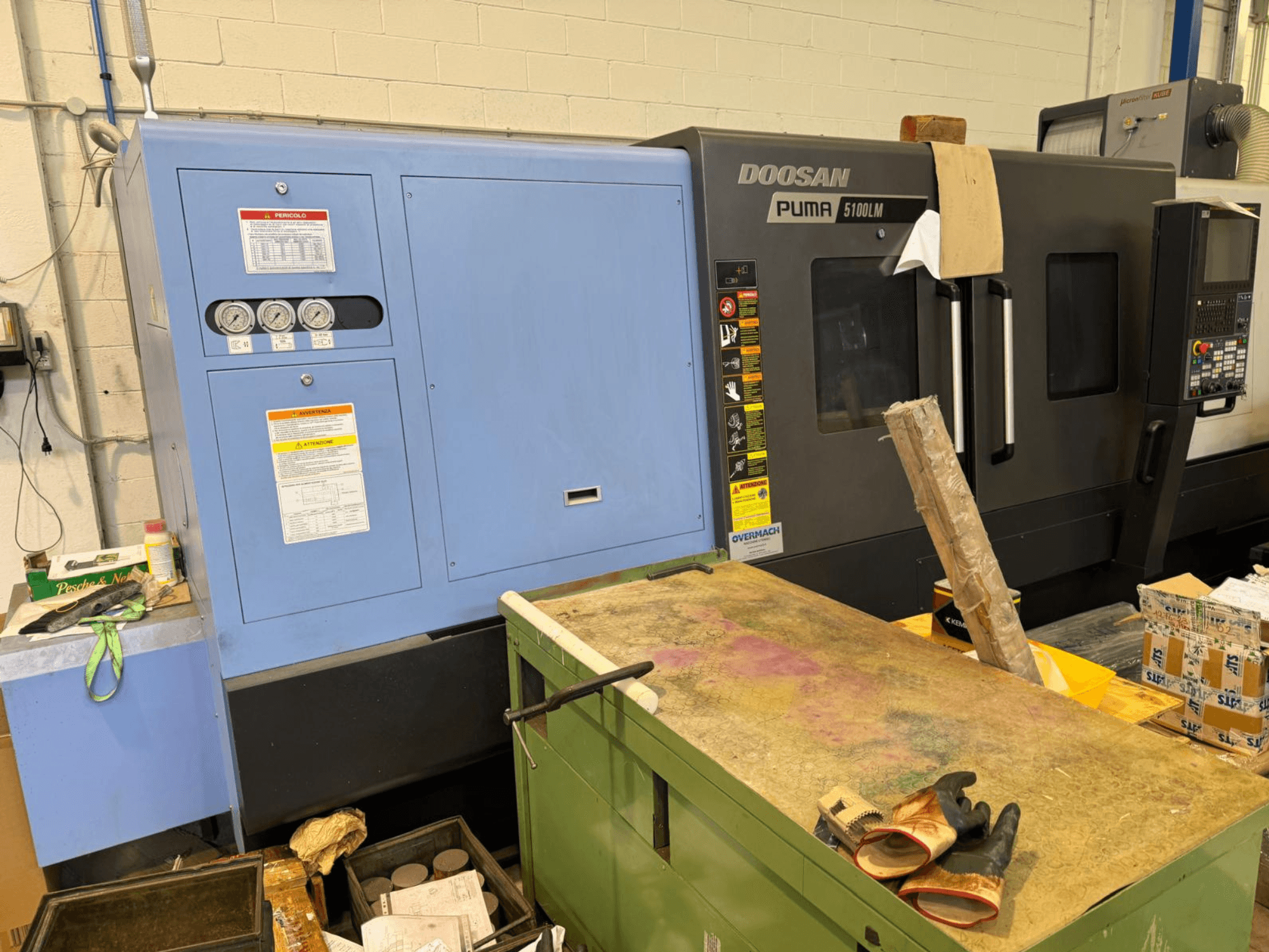 Machine CNC Doosan Puma 5100LM et panneau de commande, vue latérale. Jauges et étiquettes d'avertissement visibles sur l'unité de commande bleue.