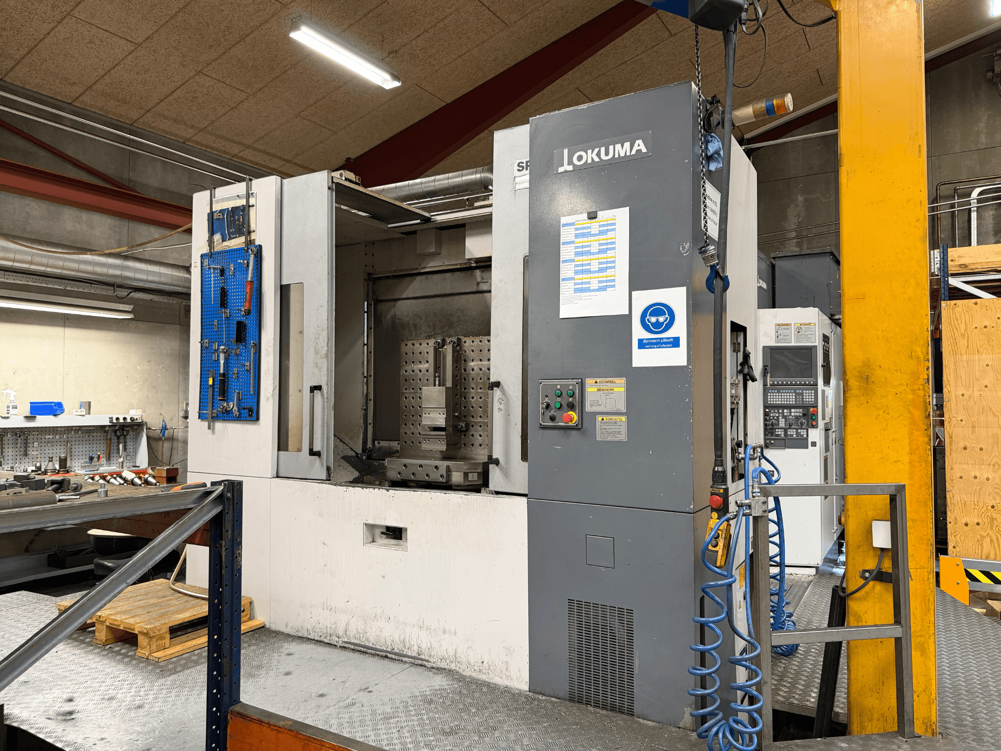 Centre d'usinage horizontal Okuma MA-600HB dans un atelier, vue de face montrant le panneau de commande et la zone de travail.