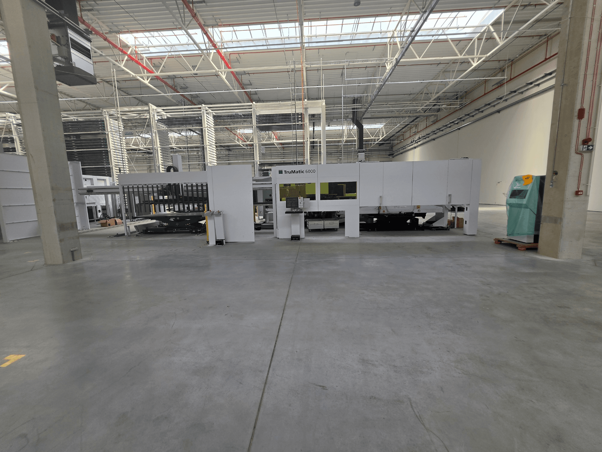 Machine combinée poinçonneuse-laser à fibre TRUMPF TruMatic 6000-1600 dans un vaste entrepôt, vue de face.