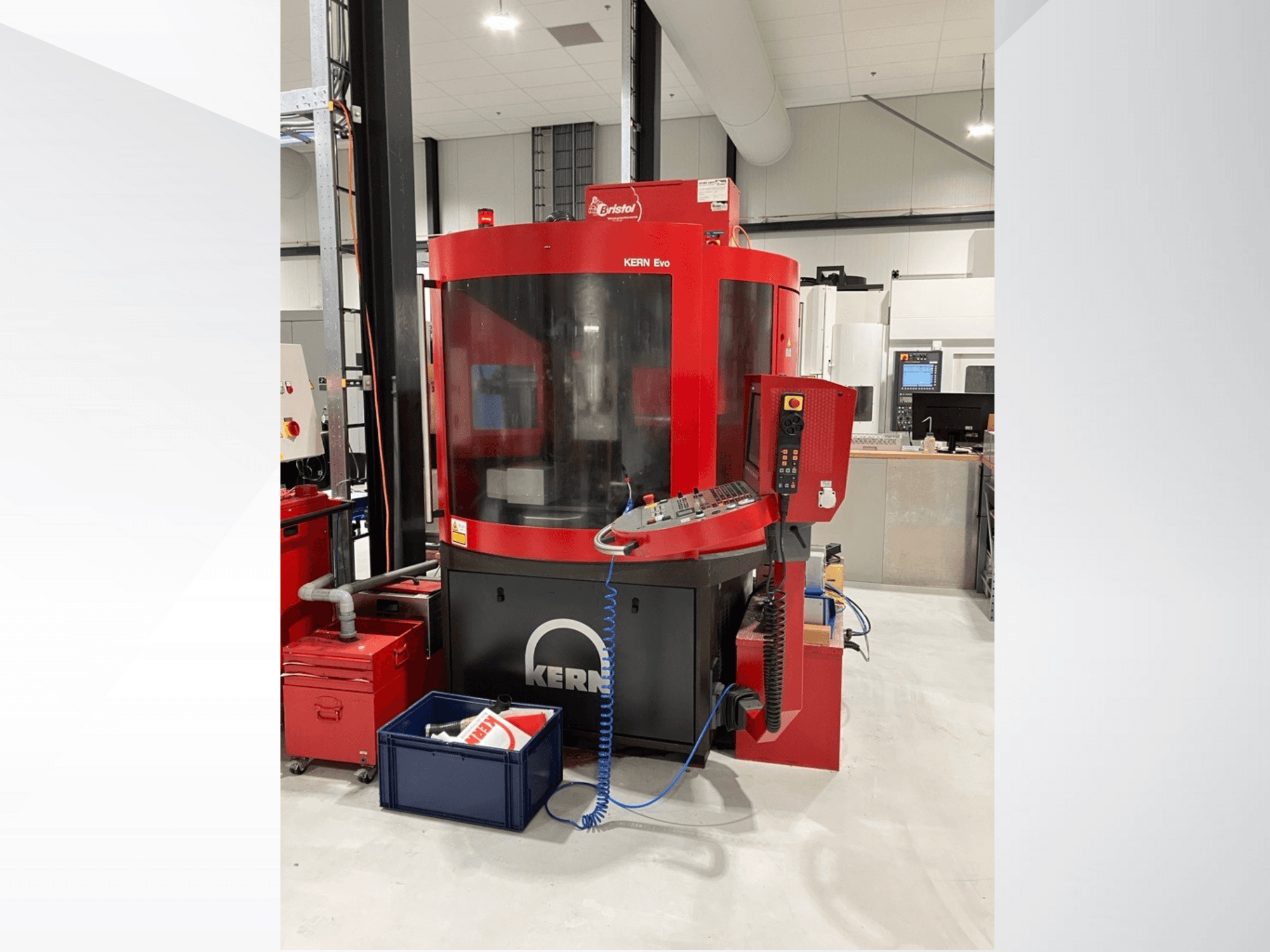 Centre d'usinage KERN Evo en rouge et noir, vue de face, montrant le panneau de commande et l'équipement environnant dans un atelier moderne.