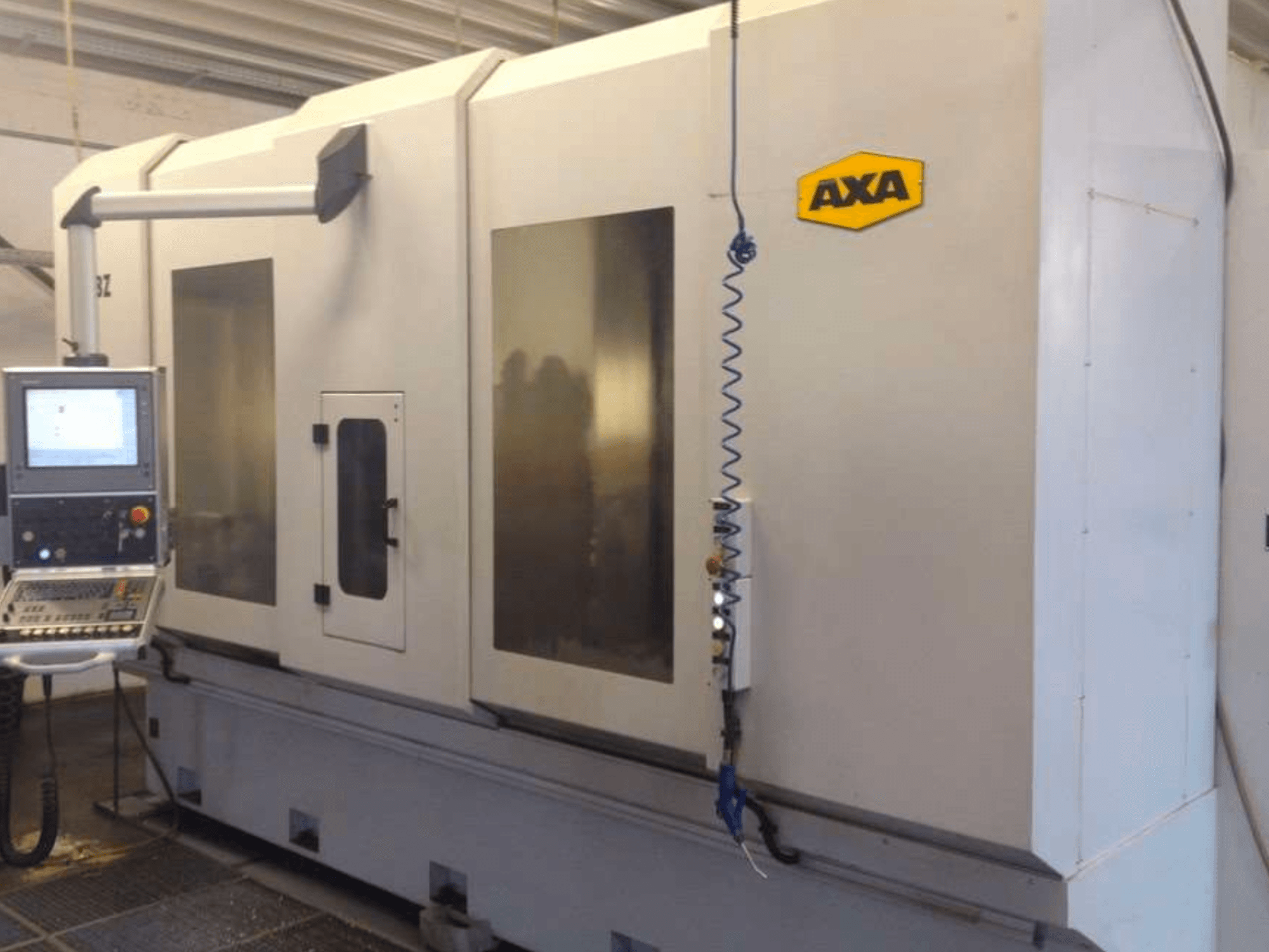 Centre d'usinage vertical AXA DBZ vu de face, avec un panneau de commande et de grandes fenêtres de sécurité transparentes.