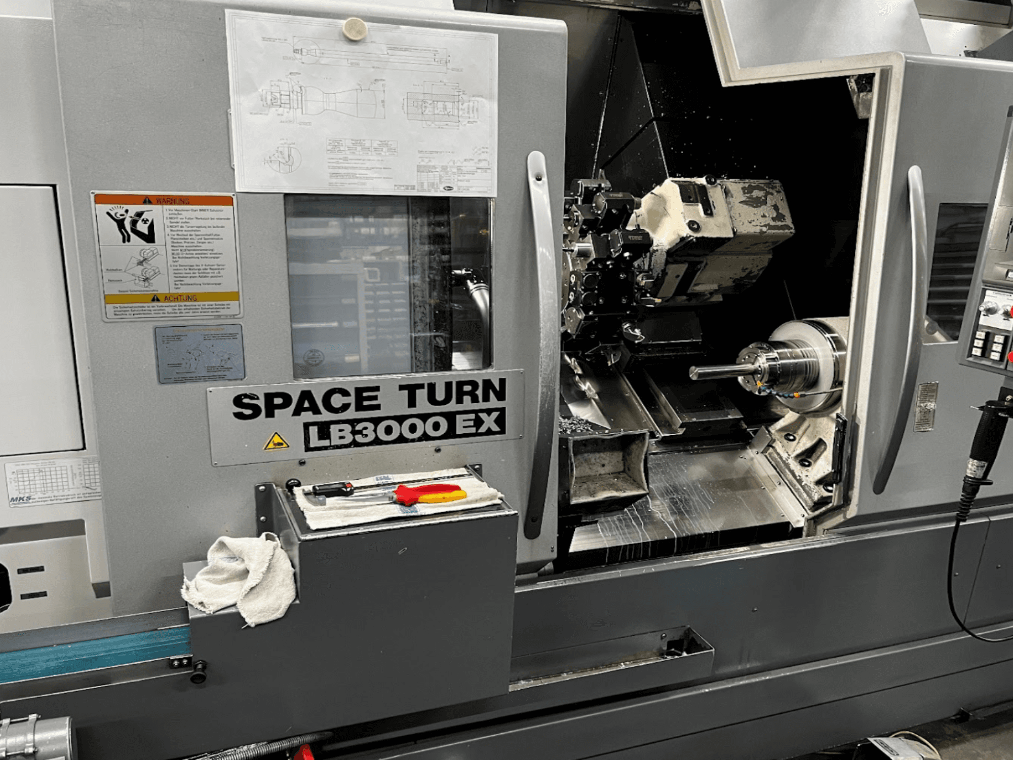 Tour horizontal Okuma LB3000EX MYW, vue de face avec panneau de commande, outils et détails de l'espace de travail visibles.