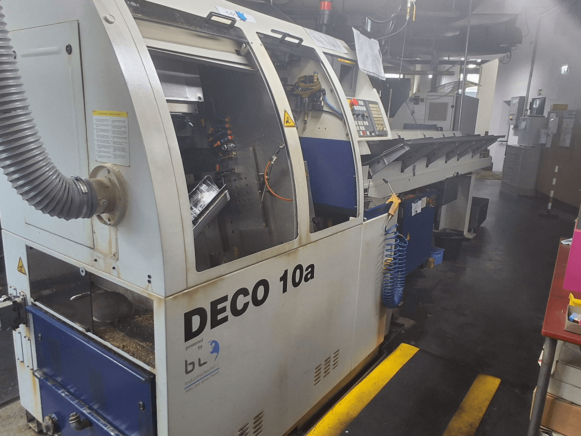 Tour de type suisse TORNOS DECO 10a, vue de face ; comprend un panneau de commande, des mécanismes visibles et un tube d'extraction de la poussière.