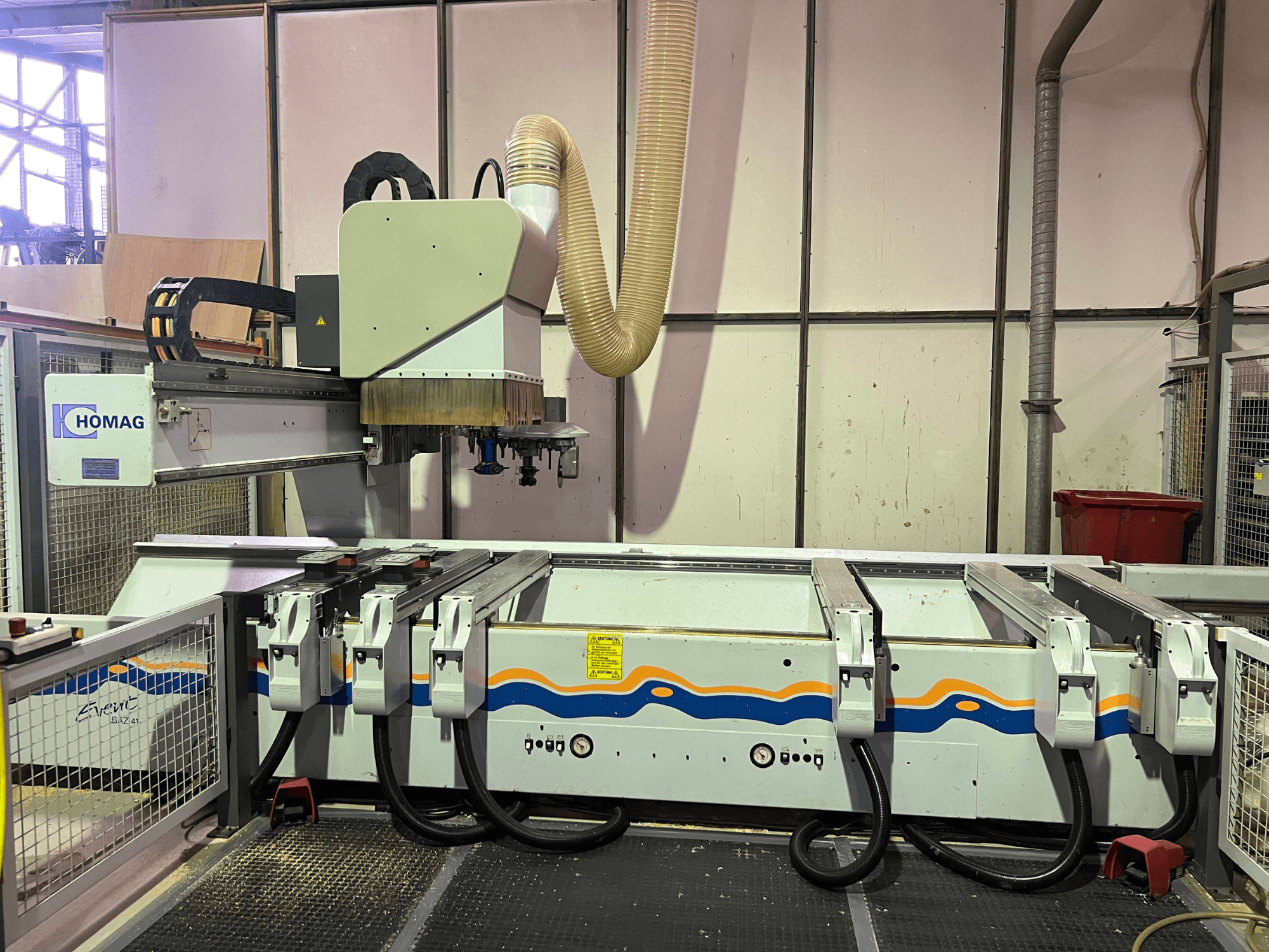 Machine CNC HOMAG BIZ 4 dans l'atelier ; vue de face montrant le système d'extraction de la poussière et le panneau de commande avec les câbles.