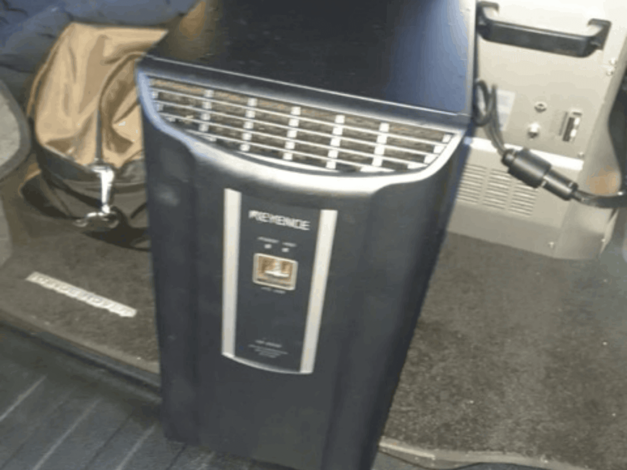 Vue frontale du système d'automatisation KEYENCE IM-8030, présentant le panneau de commande et les bouches d'aération, sur fond d'intérieur de véhicule.