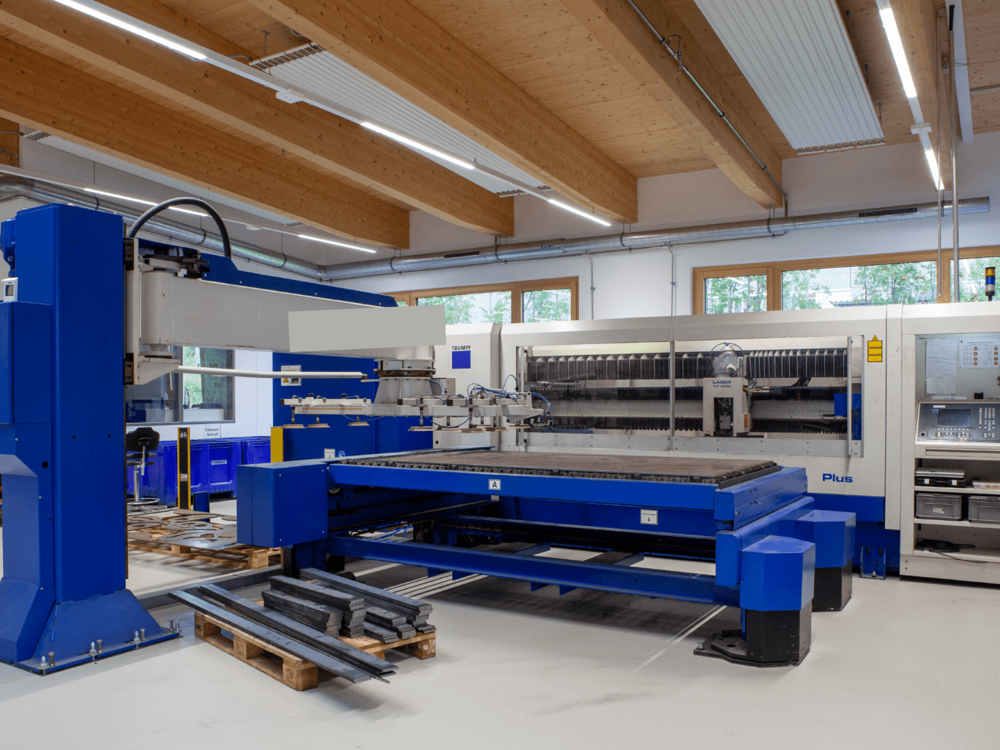 Machine de découpe laser CO₂ TRUMPF TRUMATIC L 2530 Plus dans un atelier, se distinguant par son grand plateau de découpe et son design industriel.