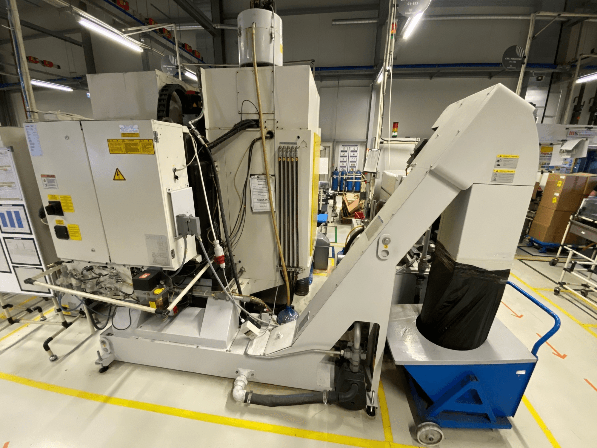 Vue de face du centre d'usinage vertical FANUC ROBODRILL α-D21LiB, mettant en évidence les composants électriques et la goulotte de sortie.