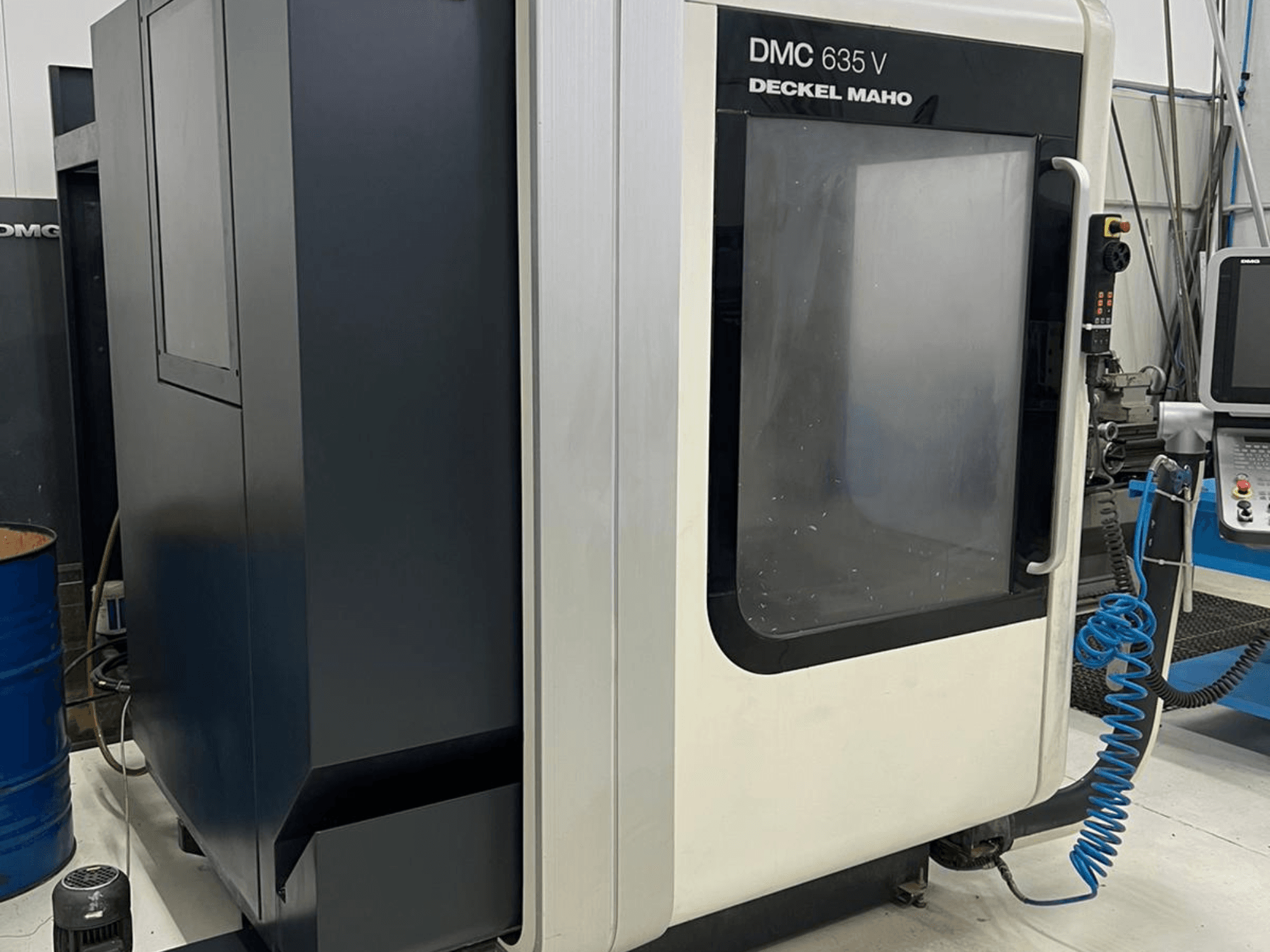 Fraiseuse DMC 635 V de Deckel Maho, vue latérale montrant le panneau de commande et la porte d'accès partiellement ouverte.