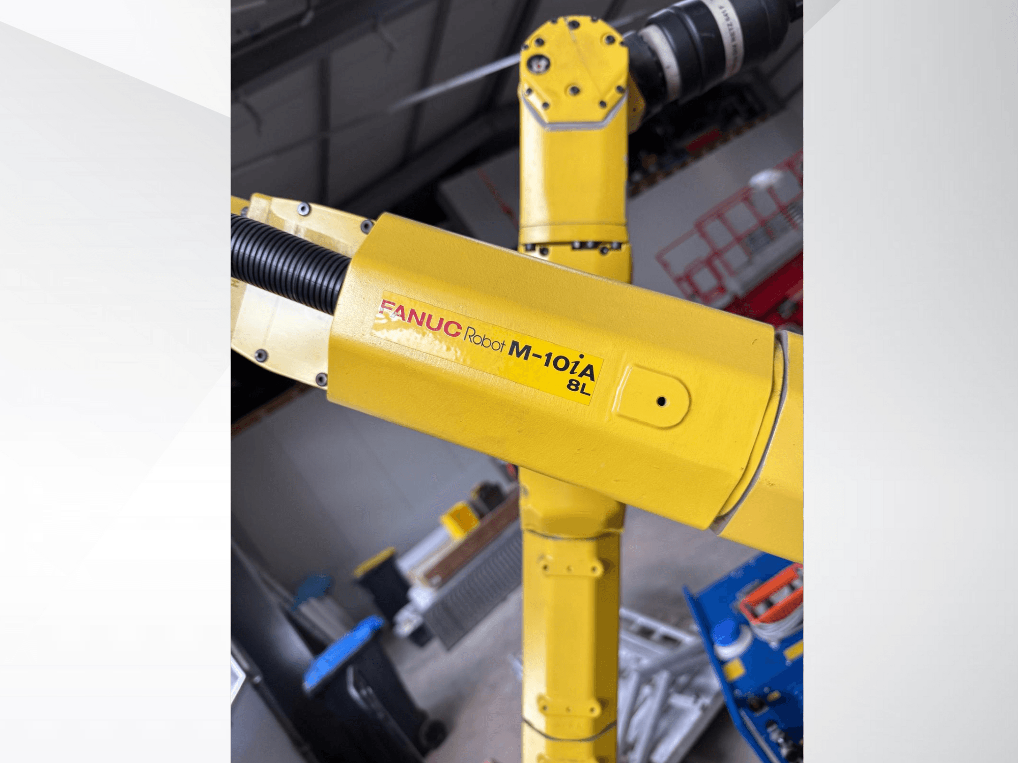 Robot FANUC M-10iA 8L en jaune, vu de côté, présentant l'articulation du bras et les composants mécaniques dans un environnement industriel.