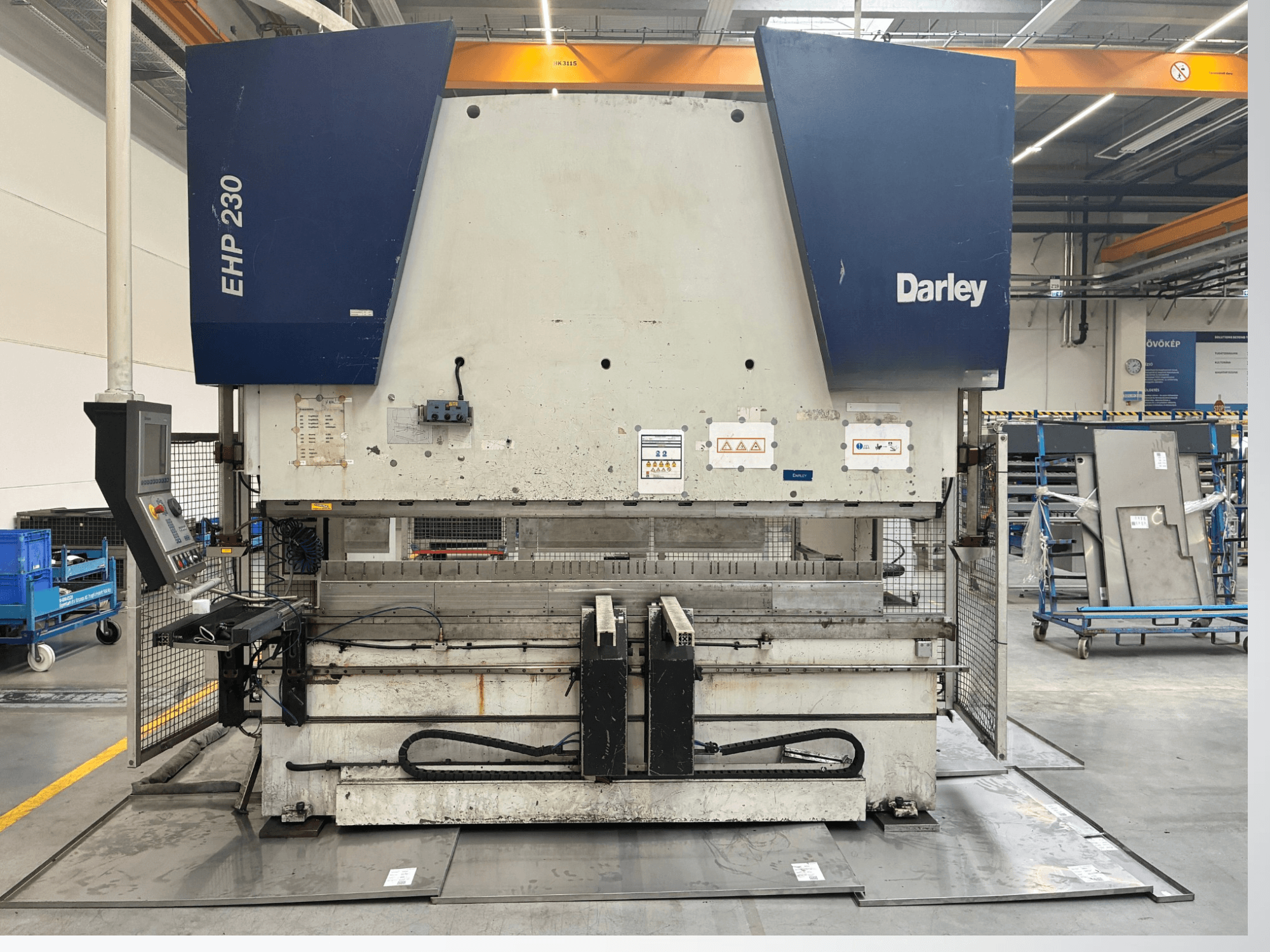 Presse hydraulique Darley EHP-LS 230.31/25, vue de face, avec panneau de commande et tôles à proximité. Idéale pour les applications industrielles.