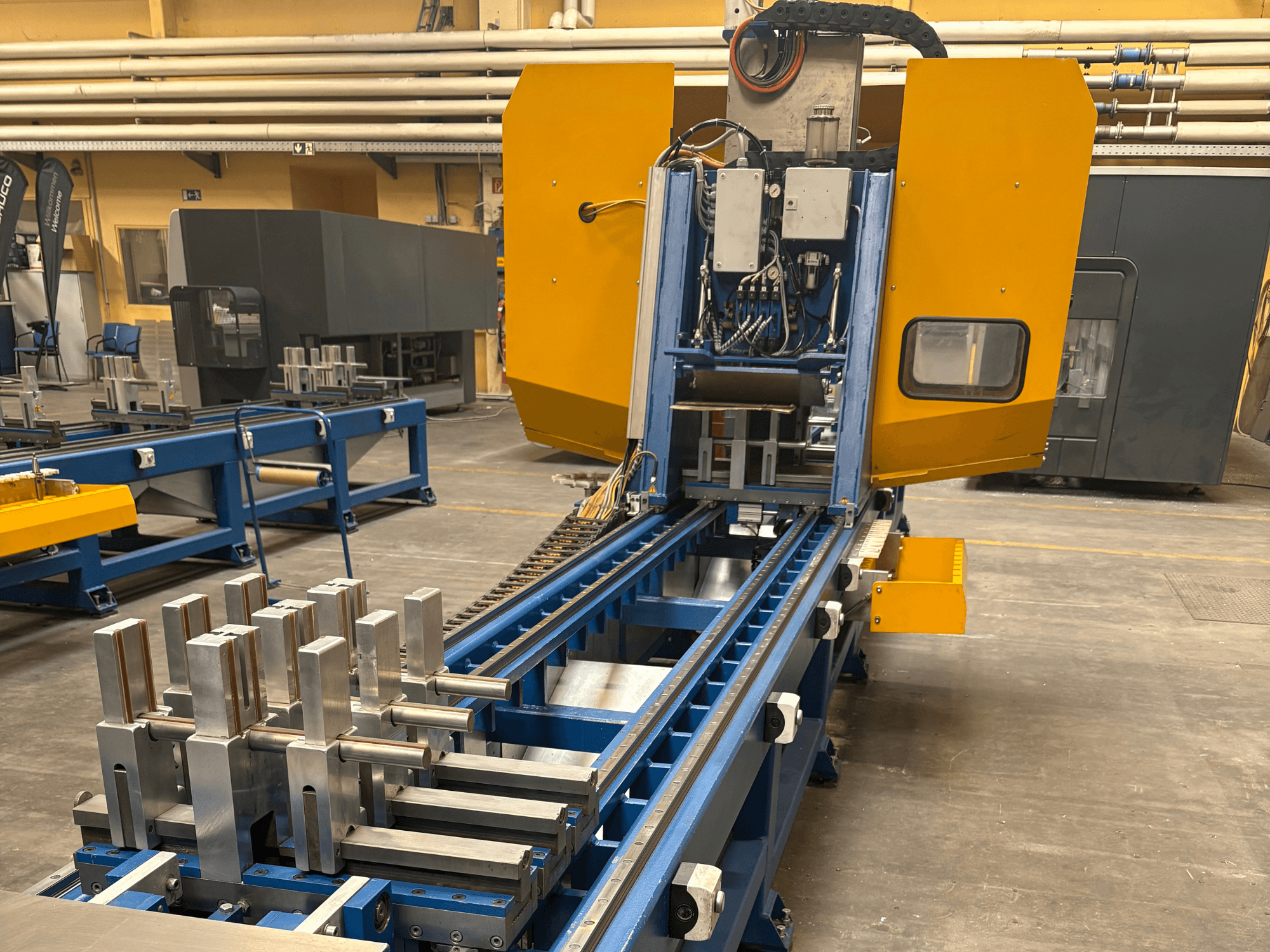 Vue avant du centre d'usinage universel SCHÜCO PBX AL, présentant des pièces métalliques sur un banc d'usinage bleu.