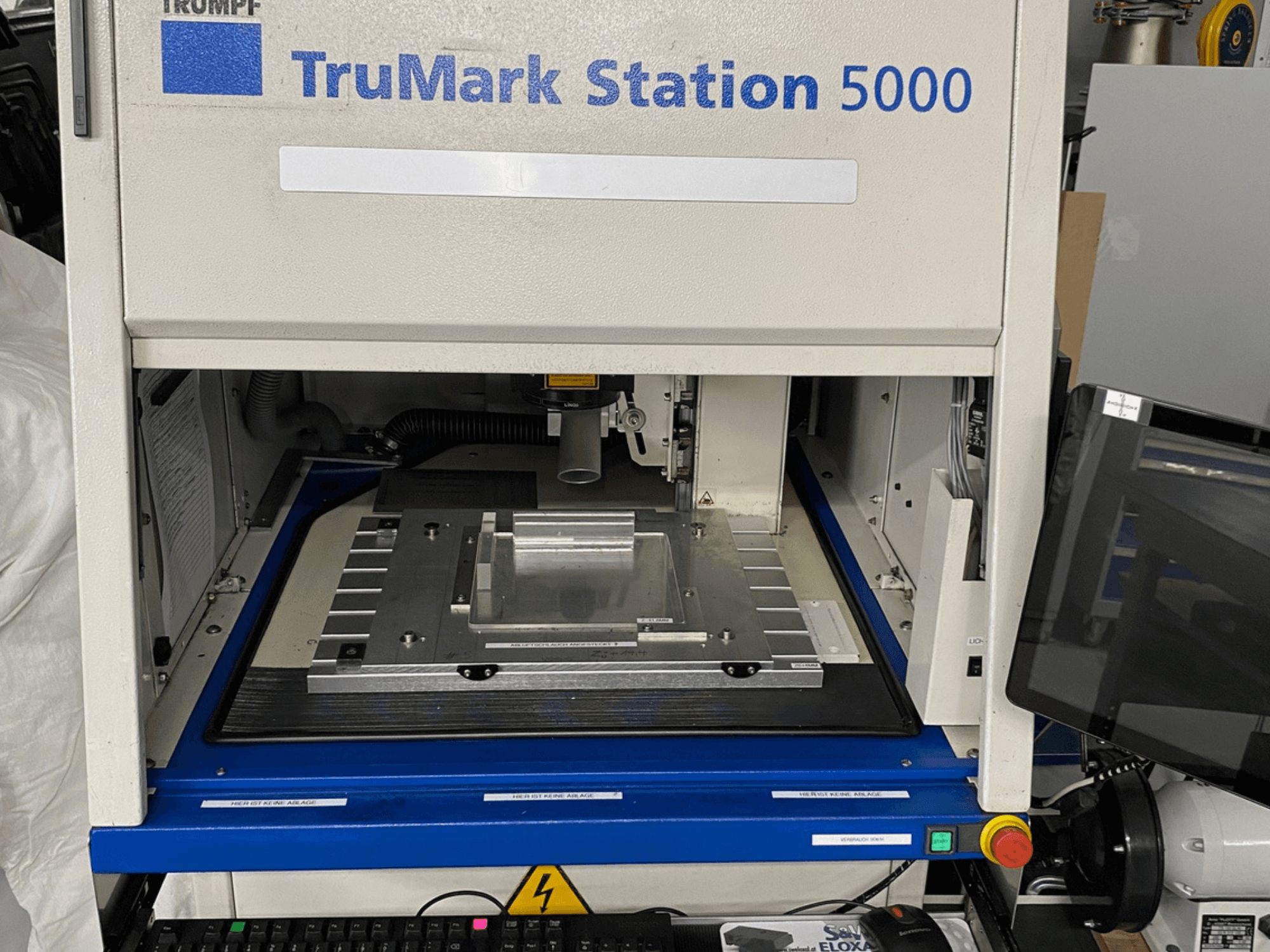Vue avant de la machine de marquage laser TruMark Station 5000 montrant la table de travail, les commandes et l'écran de contrôle.